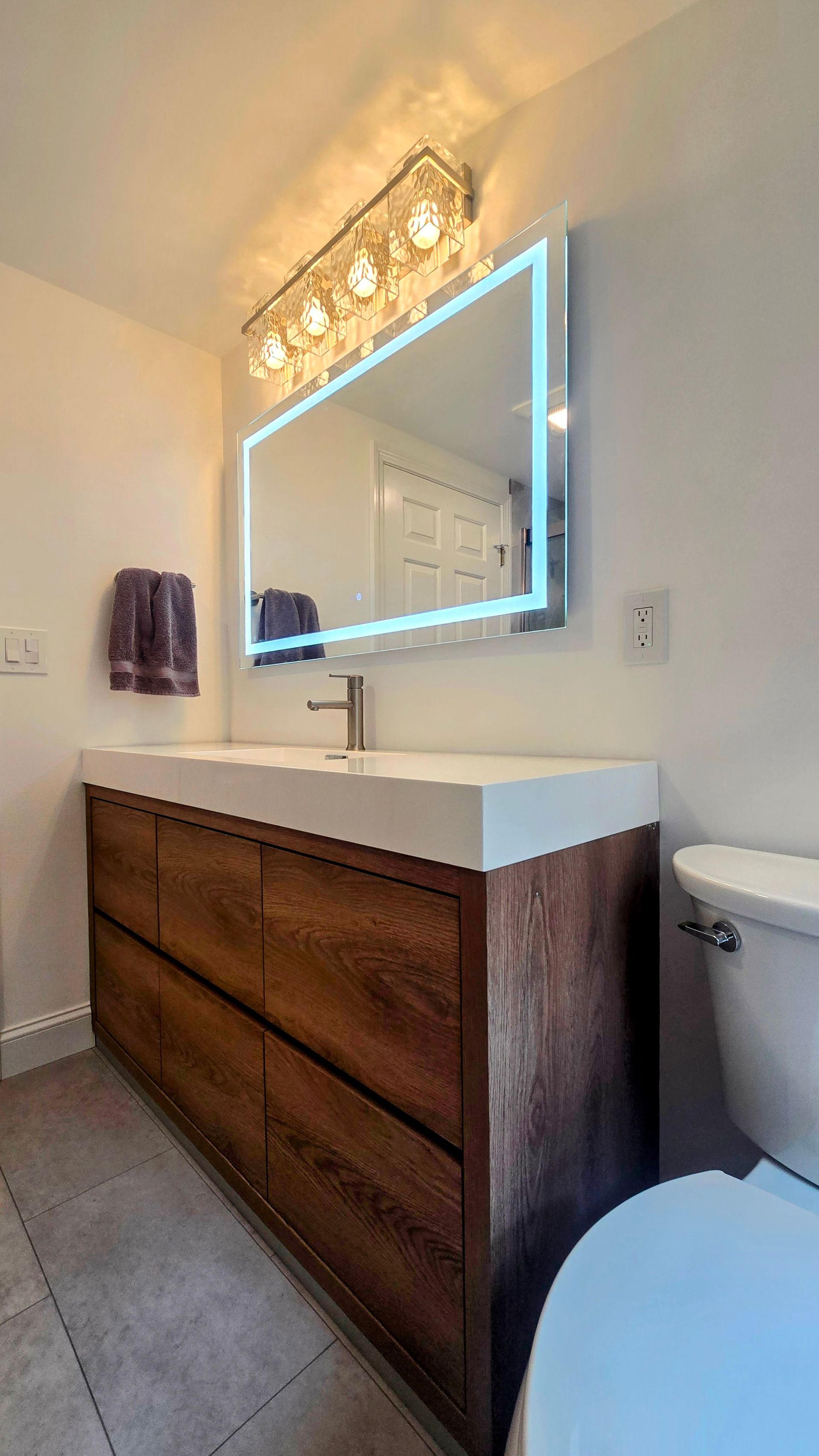 White bathroom vanity with frosted glass door panels and drawers, topped with a boat-shaped sink. Next to a white toilet.