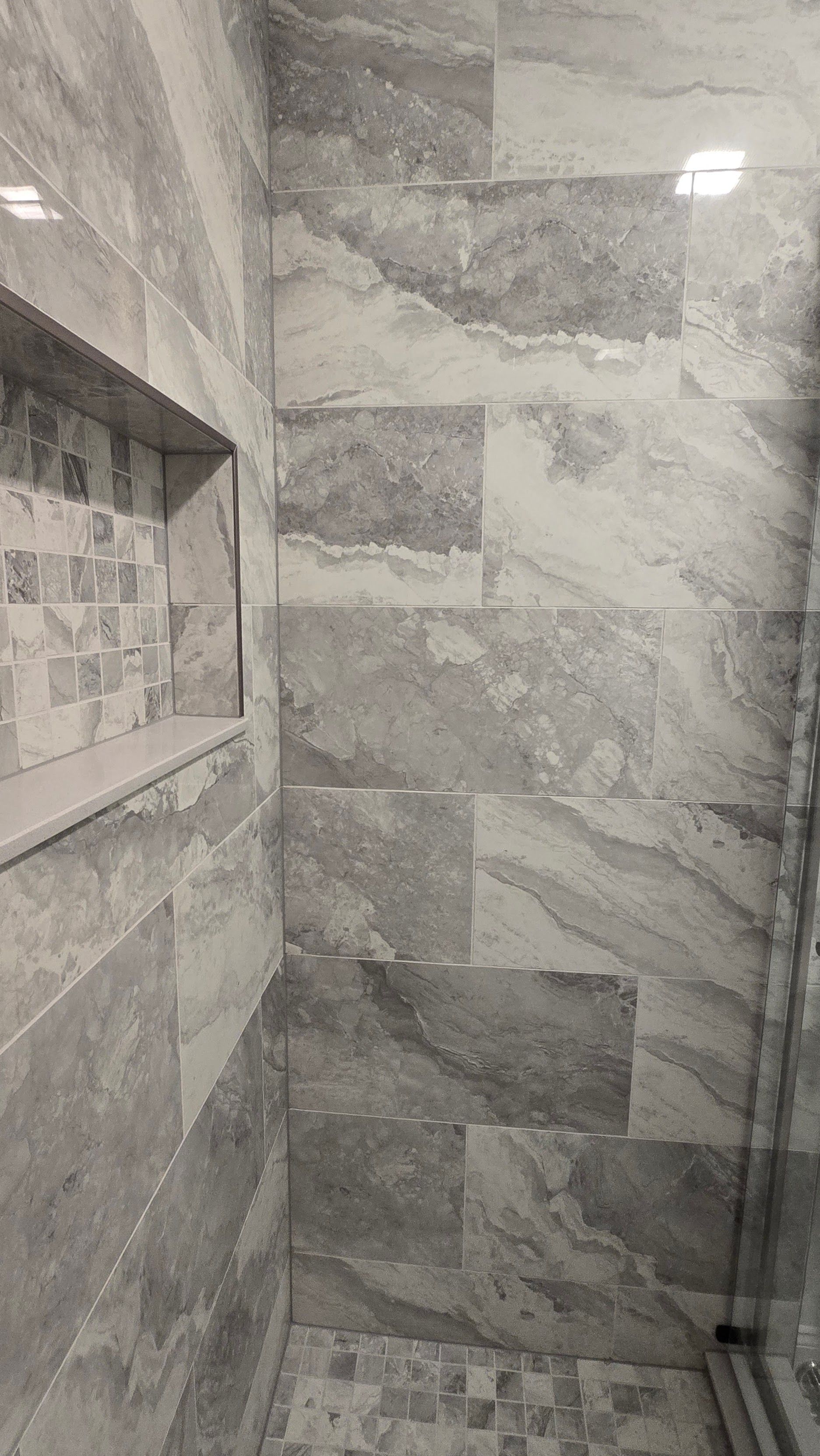 Gray and white marble tiled shower with a built-in shelf in Plainville, CT