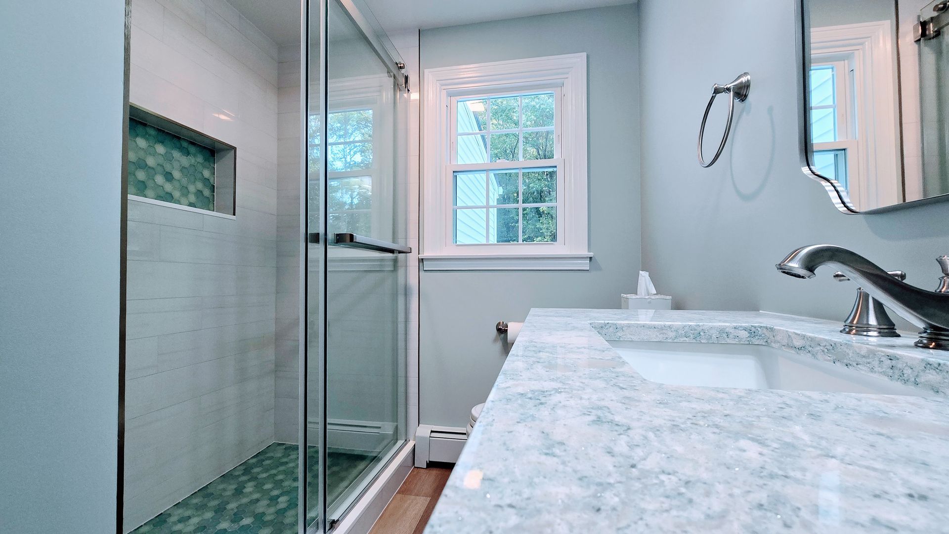 Bathroom with jacuzzi tub, vanity, toilet. Light beige walls, brown cabinets, glass shower door in Bristol, CT