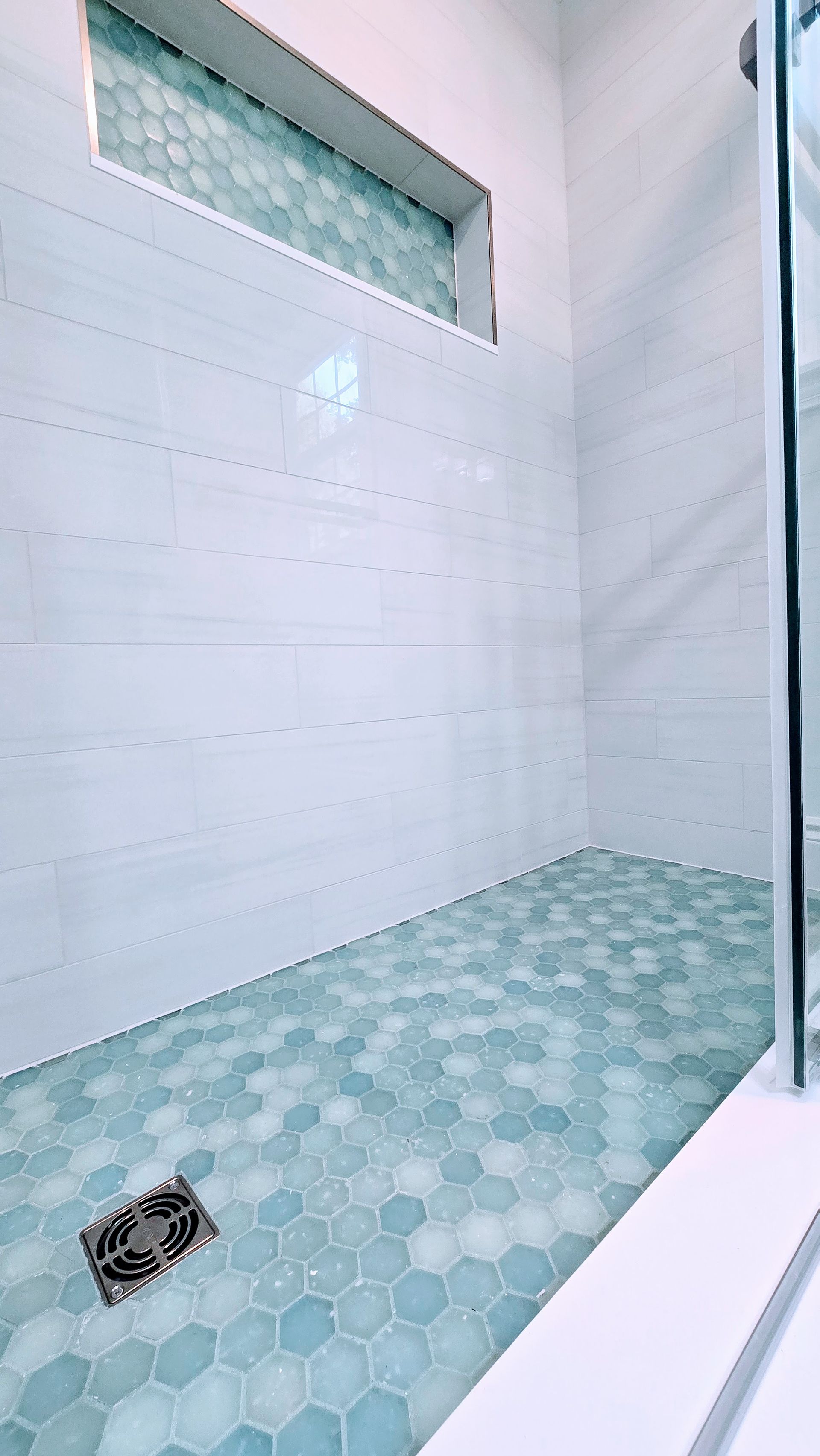 White built-in shelf with three sections in marble-tiled wall. A bar of soap rests on middle shelf in Bristol, CT