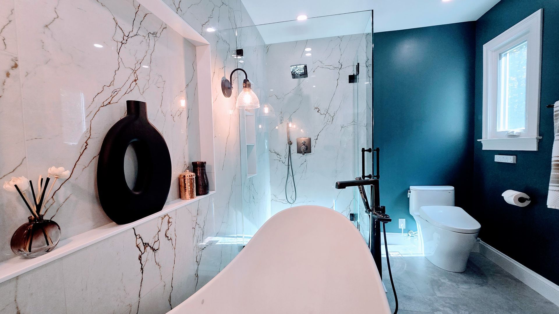 Luxurious bathroom in Avon, CT with marble-tiled walls, a soaking tub, and a dark blue accent wall.