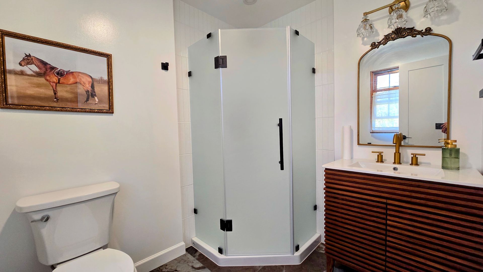 Bathroom remodel in Simsbury, CT with shower, vanity, toilet, and horse painting. White walls, gold fixtures, and dark wood vanity.