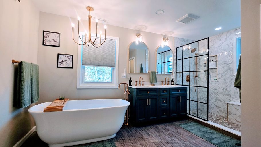 Stylish bathroom in Simsbury, CT with a white tub, dark vanity, and black shower enclosure.