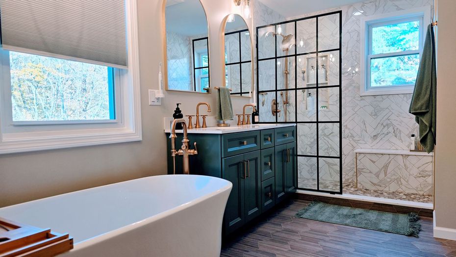 Modern bathroom  in Simsbury, CT with a freestanding tub, dark green vanity, and black-framed shower.