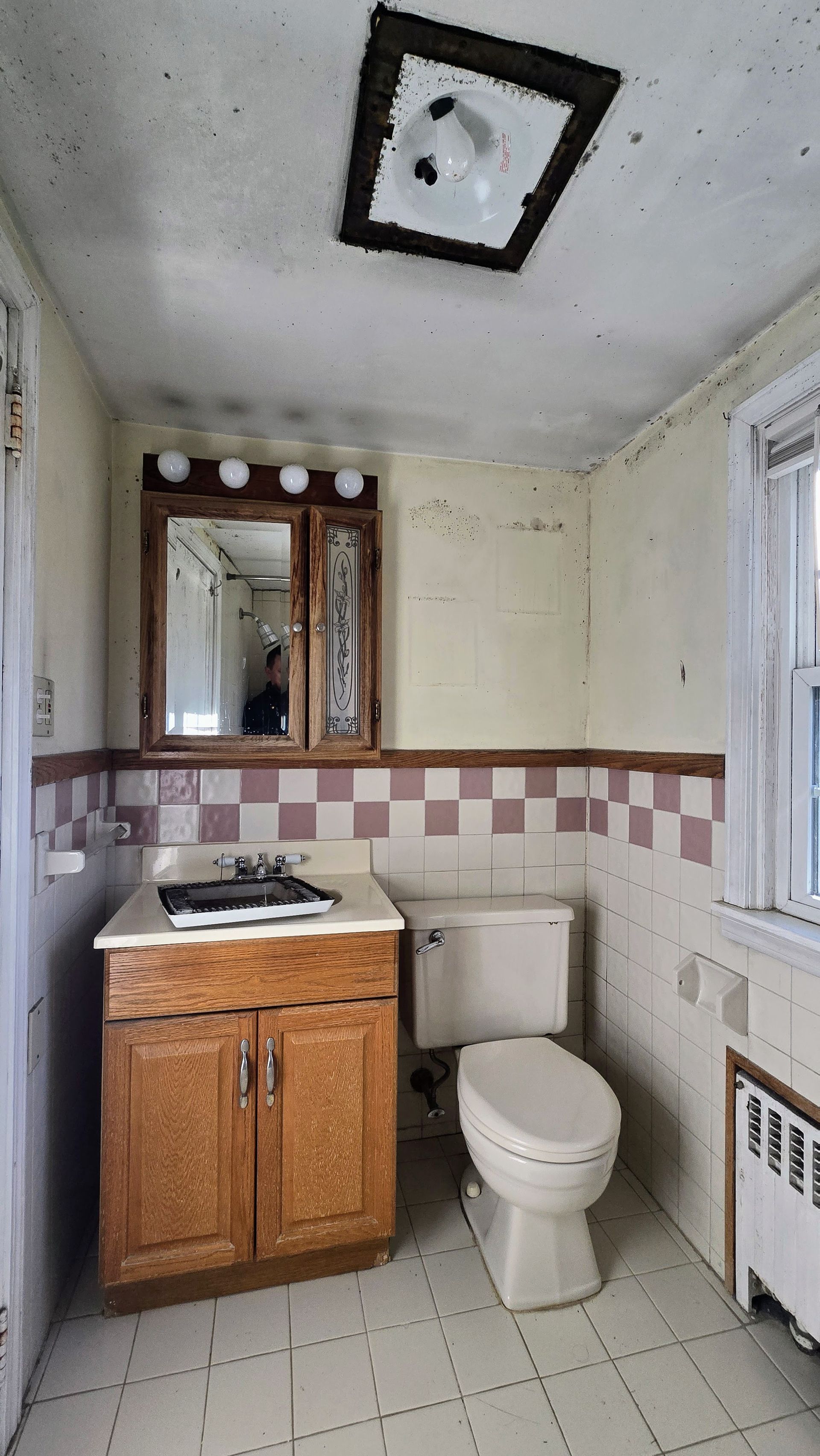 Small Southington CT bathroom with wooden vanity, toilet, and checkered wall trim.