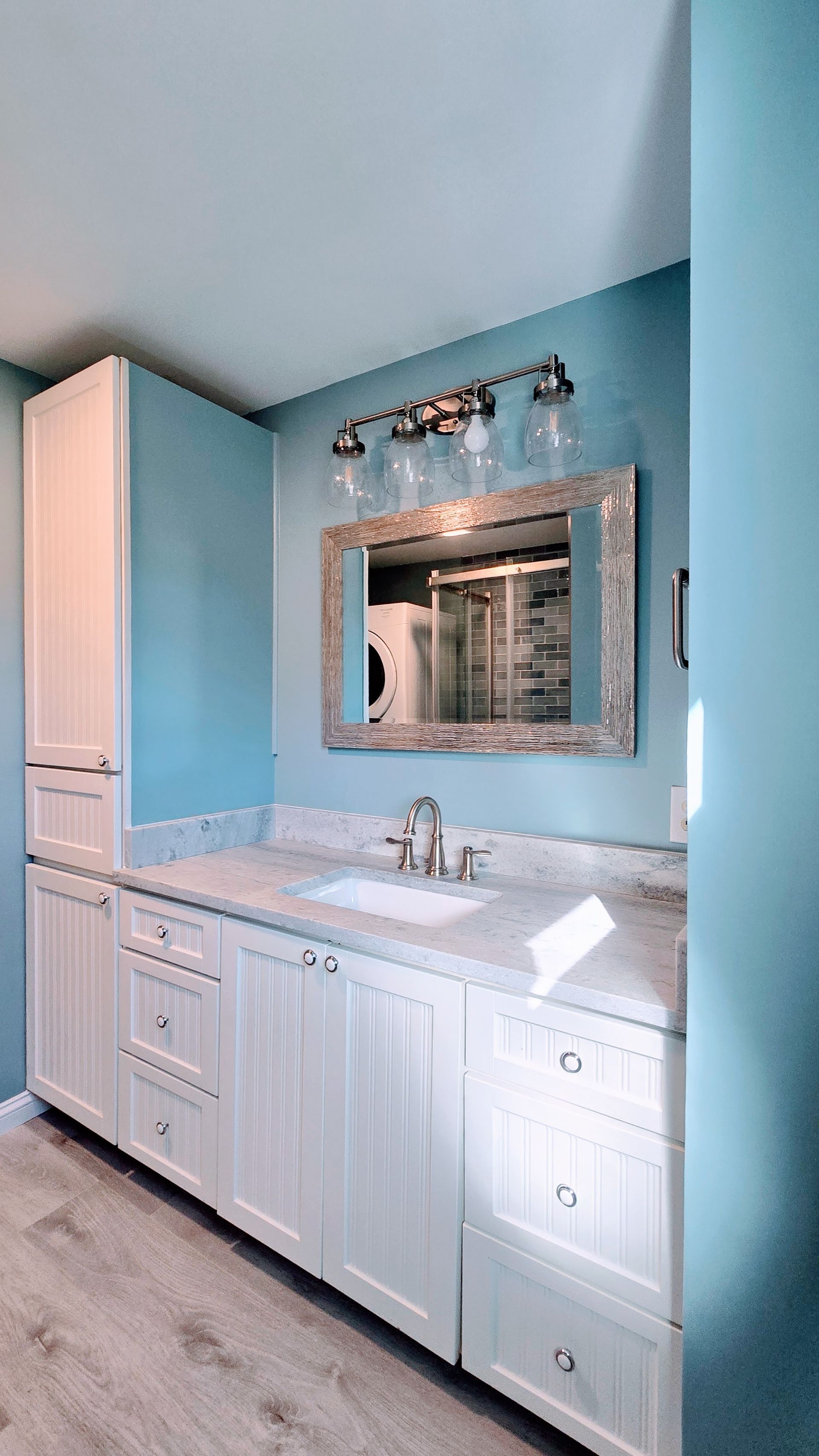 Small bathroom remodel in Ashford, CT with white cabinets, blue walls, a mirror, and a vanity sink.