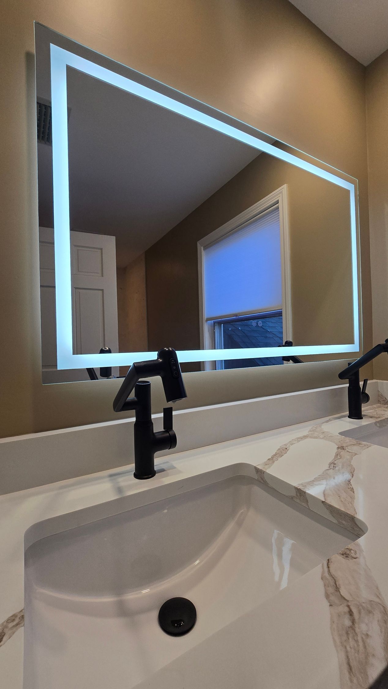 Dark blue bathroom vanity in Wolcott, CT  with gold fixtures, arched mirrors, and marble tile shower.