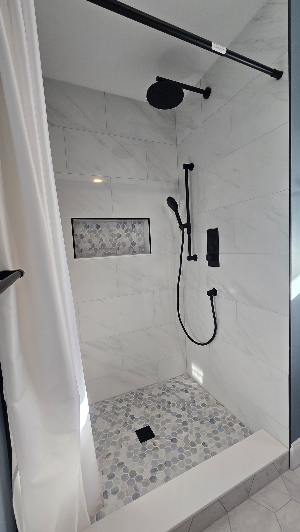 Berlin bathroom vanity with black fixtures, lit mirror, and neutral walls.