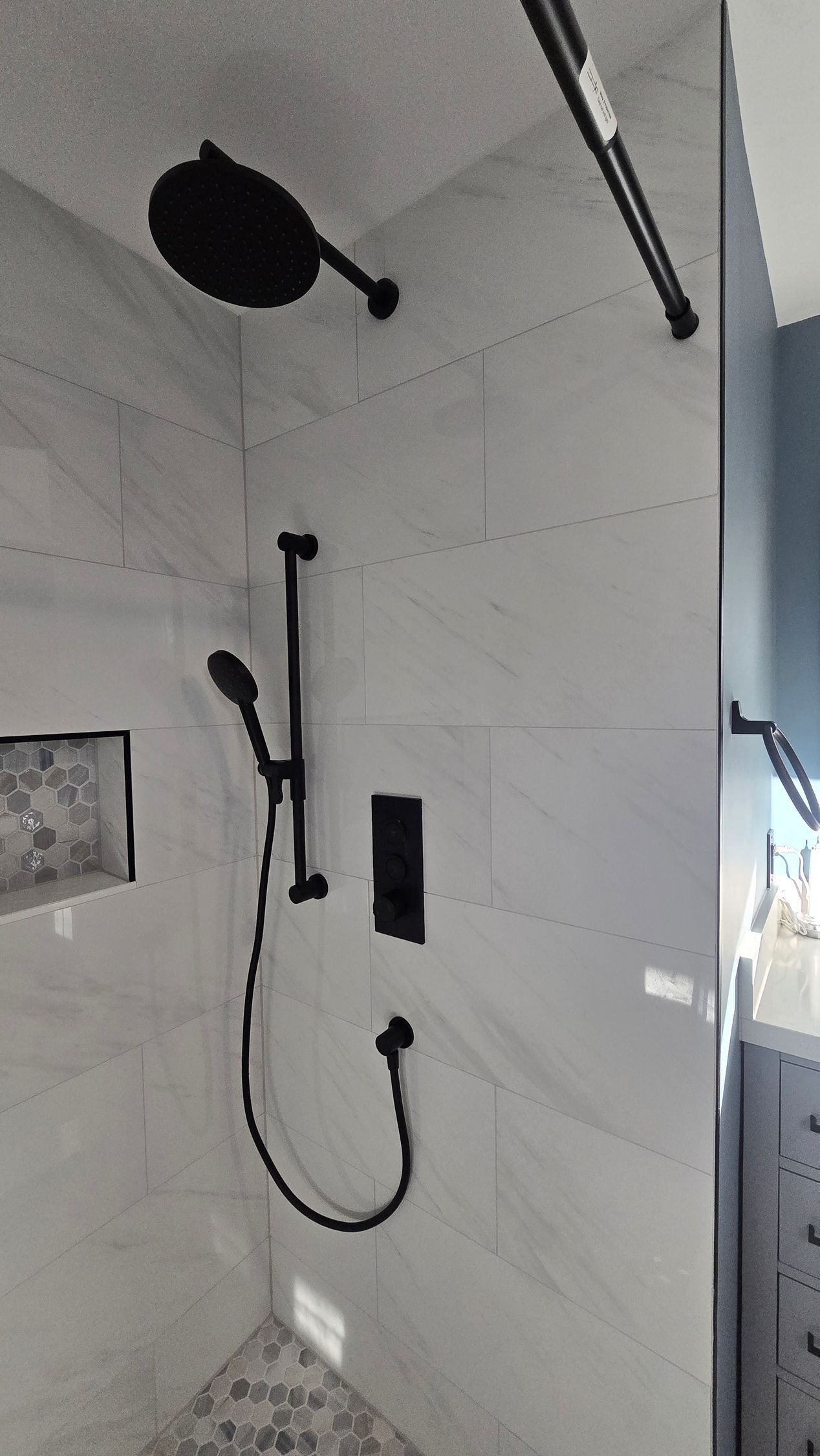Bristol bathroom with white tub, speckled tile wall, black shower fixtures, and a recessed shelf.