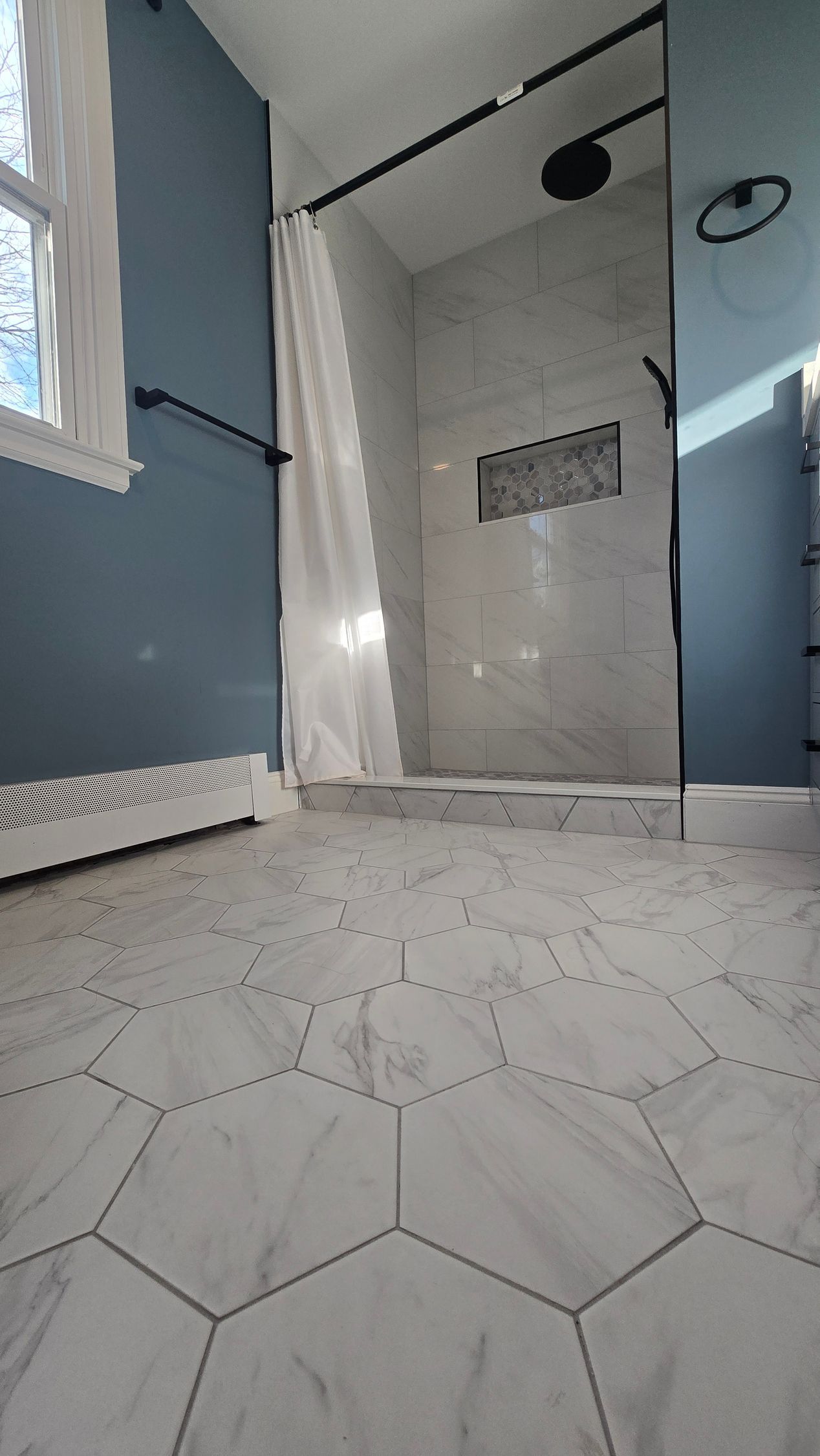 Hallway with doorway to Bristol bathroom. Pink tile floor, white door, beige walls.