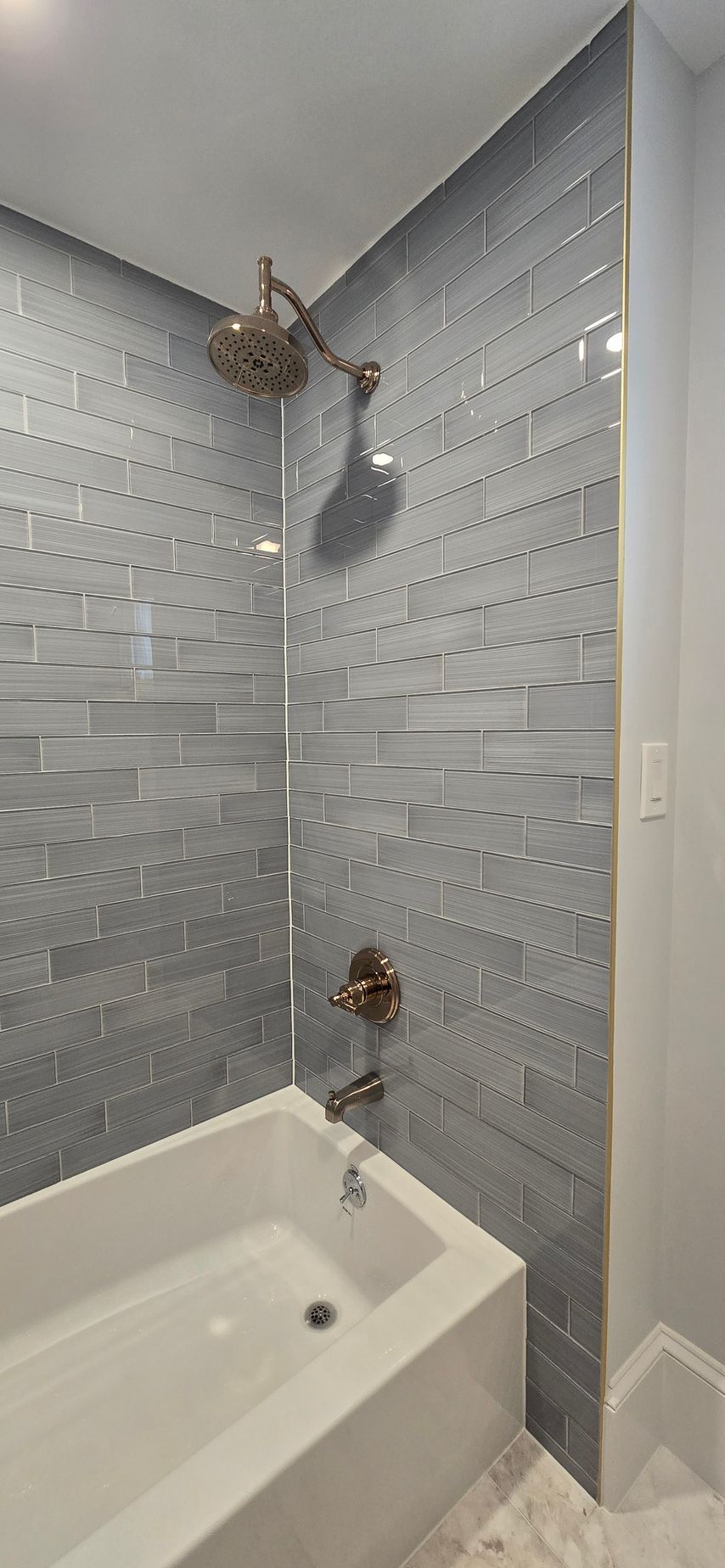 Newington CT grey tiled bathroom, with a bathtub and silver items.