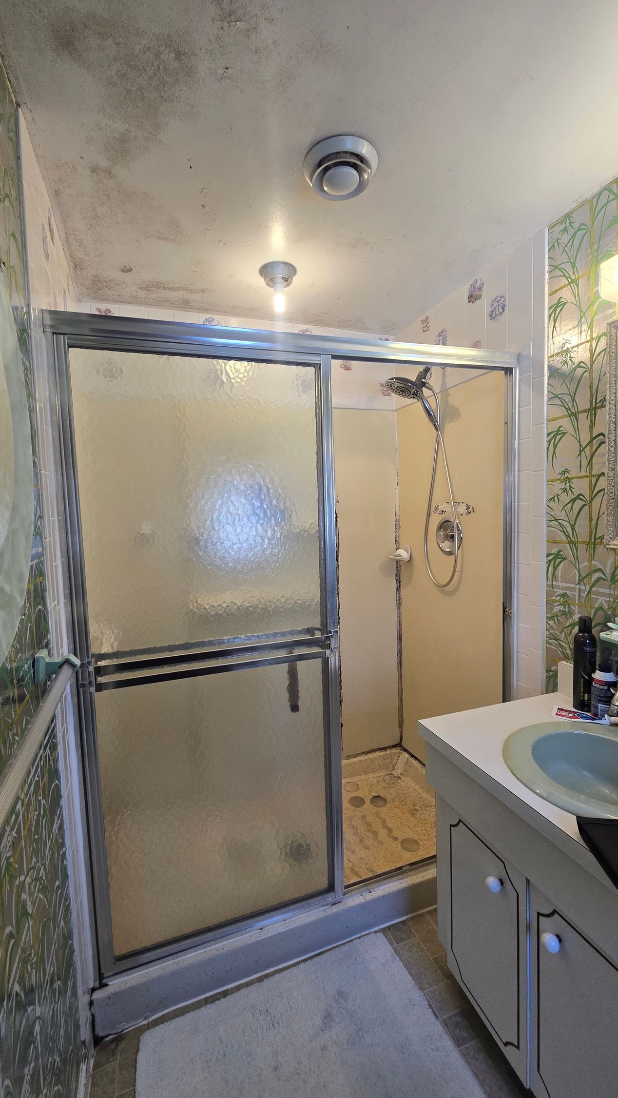 Shower stall with frosted sliding glass door in a small beige bathroom