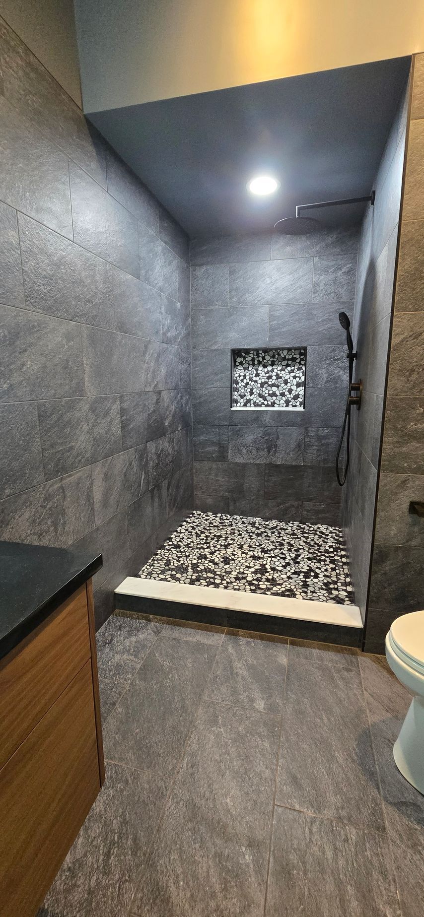 Bristol bathroom with white tub, speckled tile wall, black shower fixtures, and a recessed shelf.