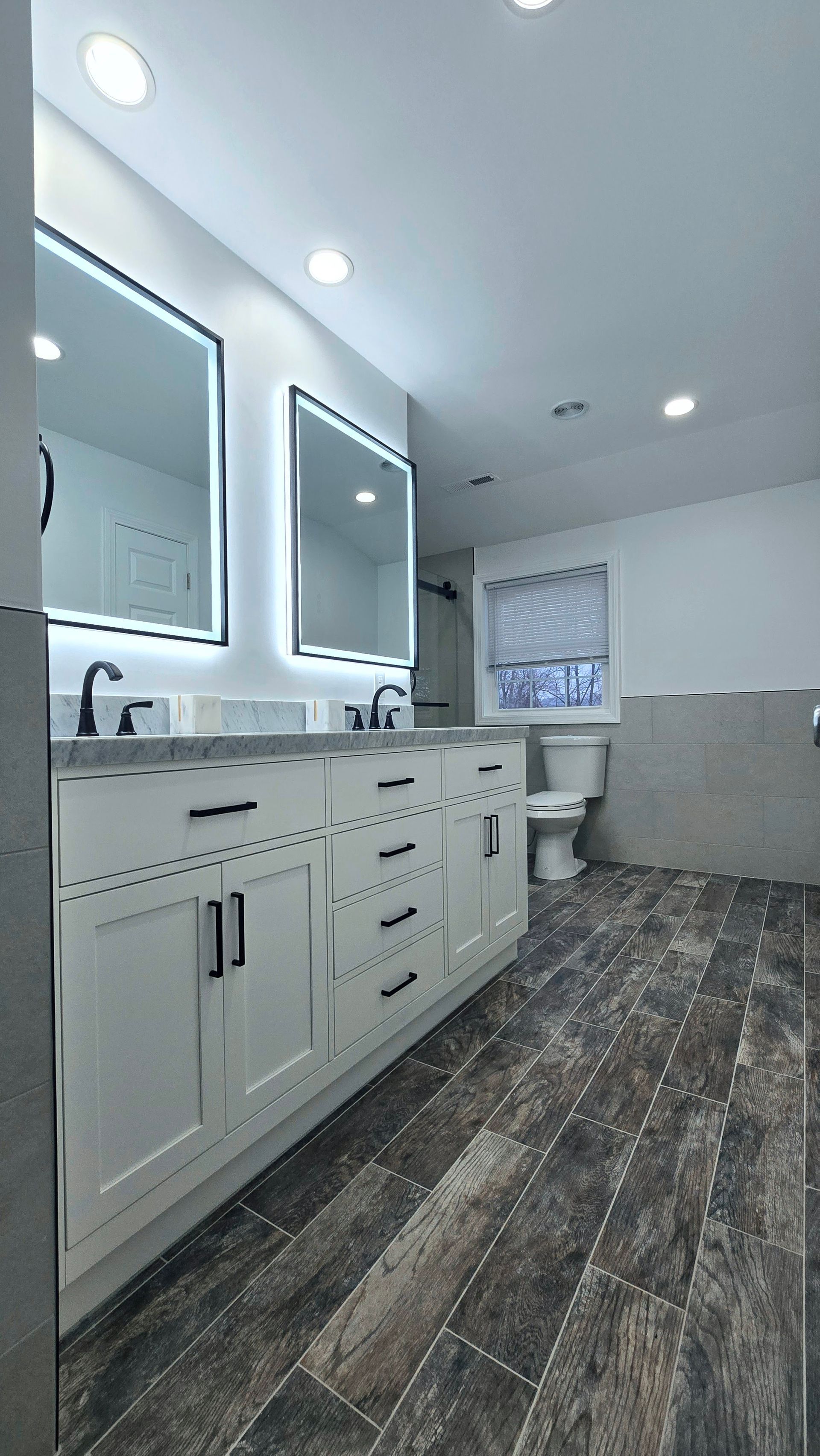 Shower interior in Berlin, CT with mosaic floor and wall tiles. A built-in shelf displays the same mosaic. Black fixtures.