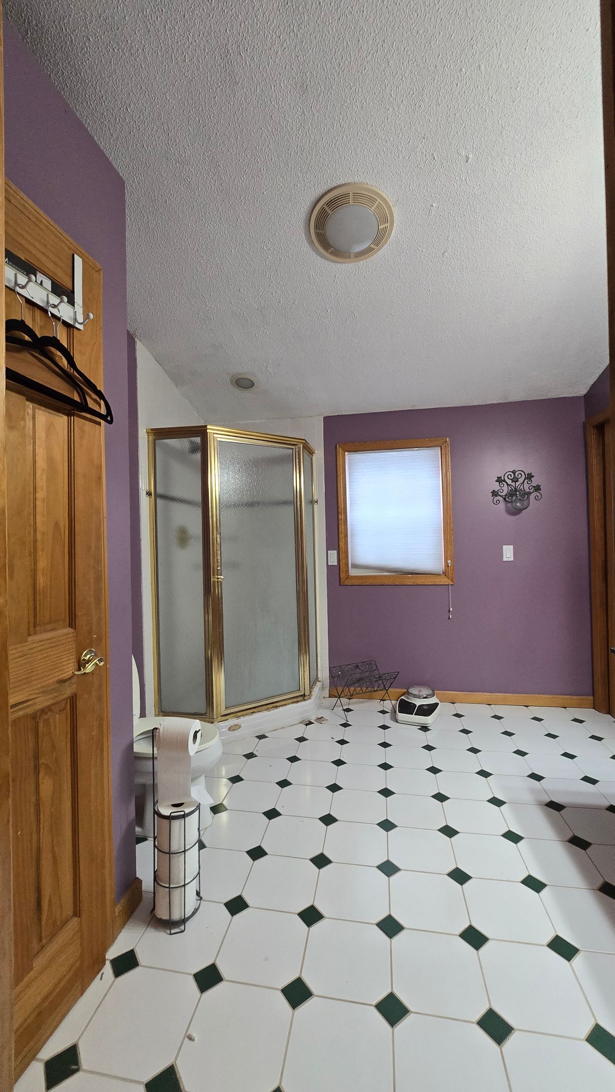 Purple bathroom with tiled floor, shower stall, window, and wooden door.