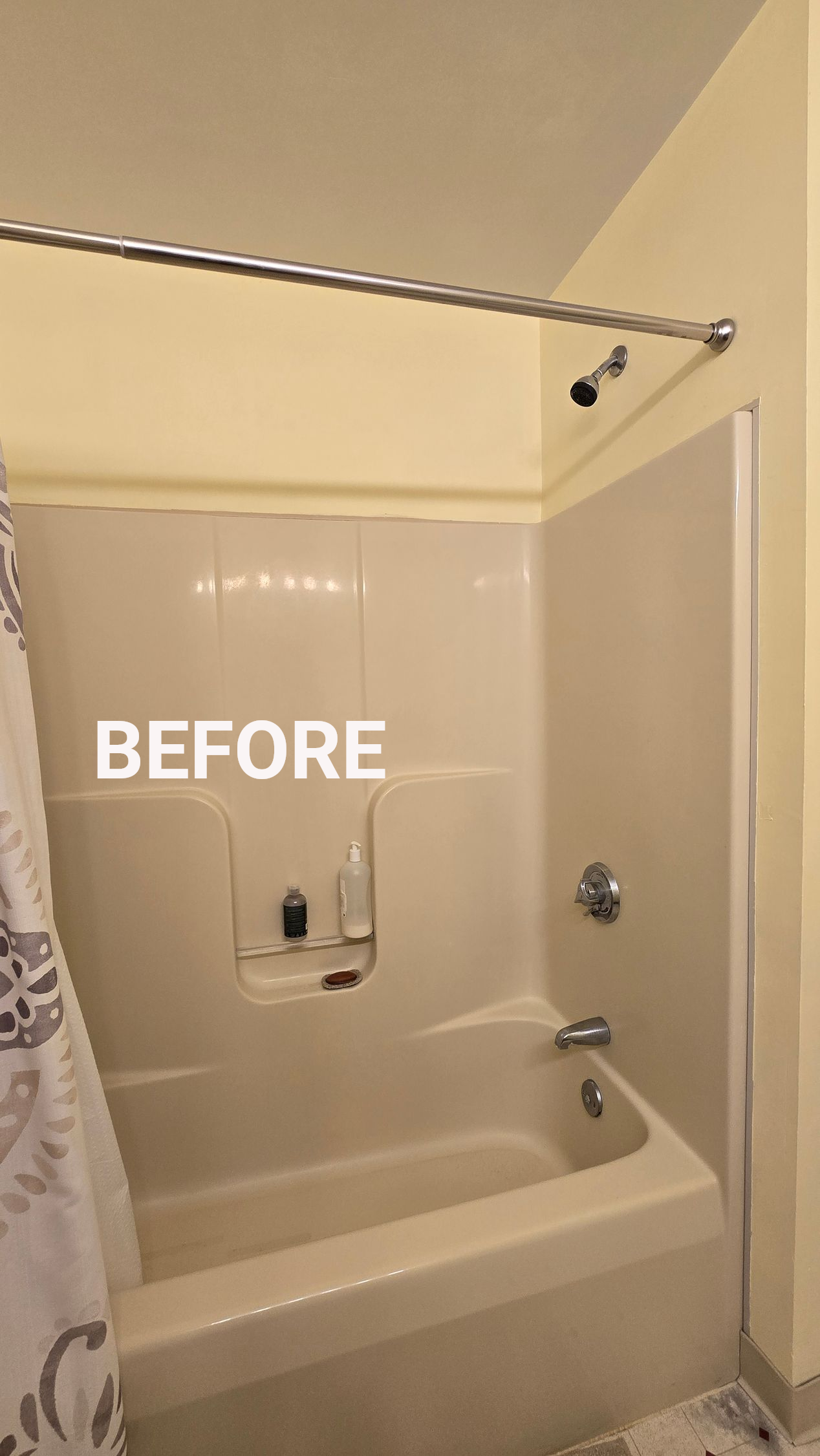 Cream-colored bathtub with shower curtain, grab bars, and tiled surround in a bathroom.