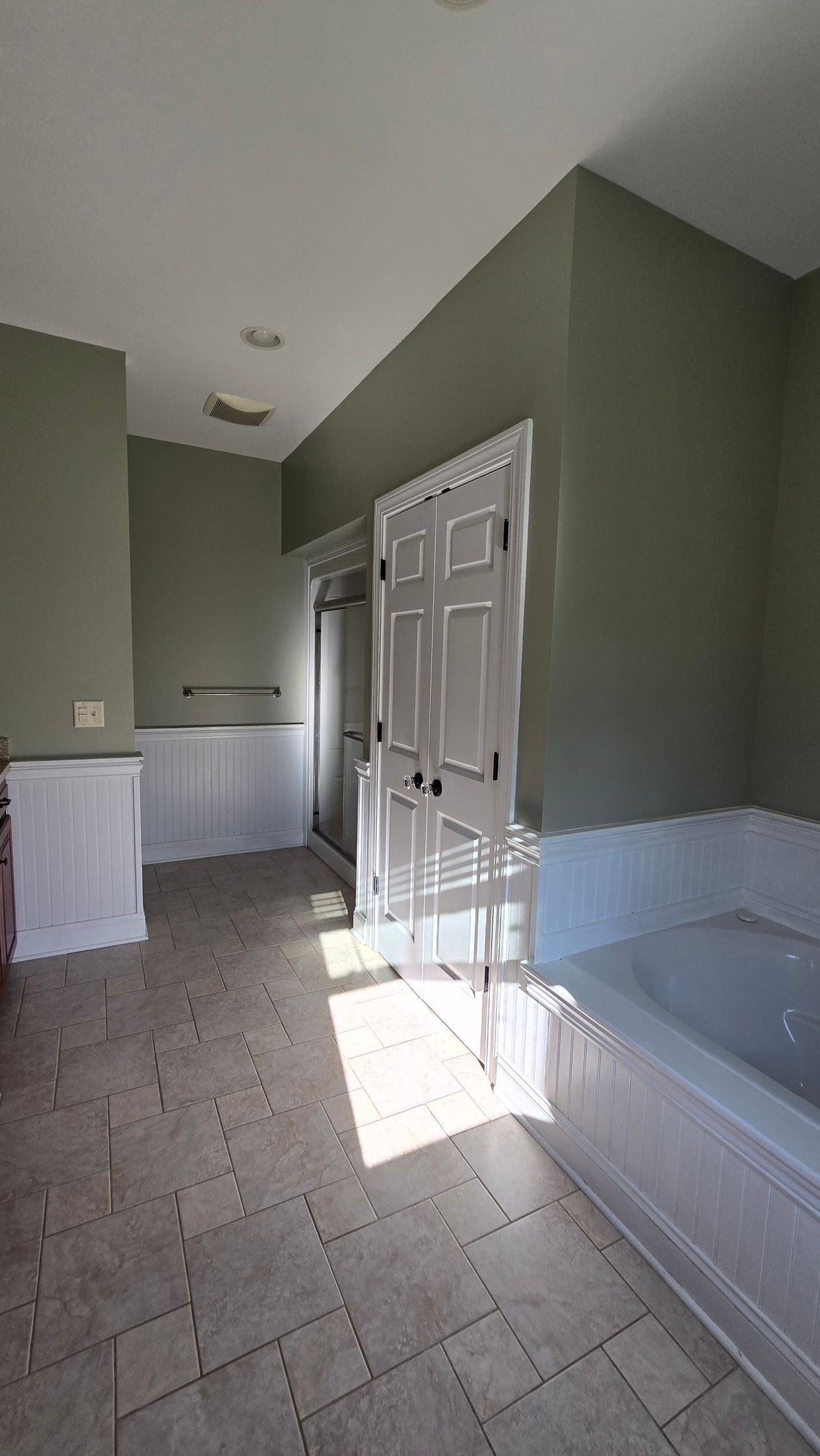 BEFORE Bathroom with gray walls, white tub and door, tiled floor, and sunlight streaming in. By First Choice Bathroom Remodeling done in Haddam, CT.