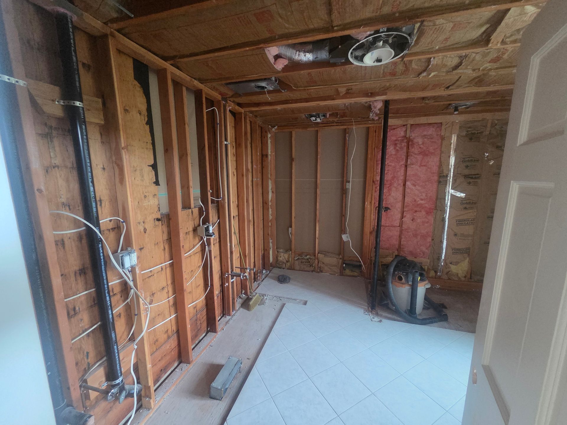 Unfinished room with exposed wall studs, insulation, and tools on the floor during renovation