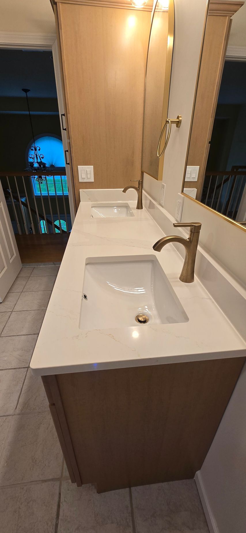 Bathroom vanity with white countertop, built-in sink, bronze faucet, and wall mirror in a small room.