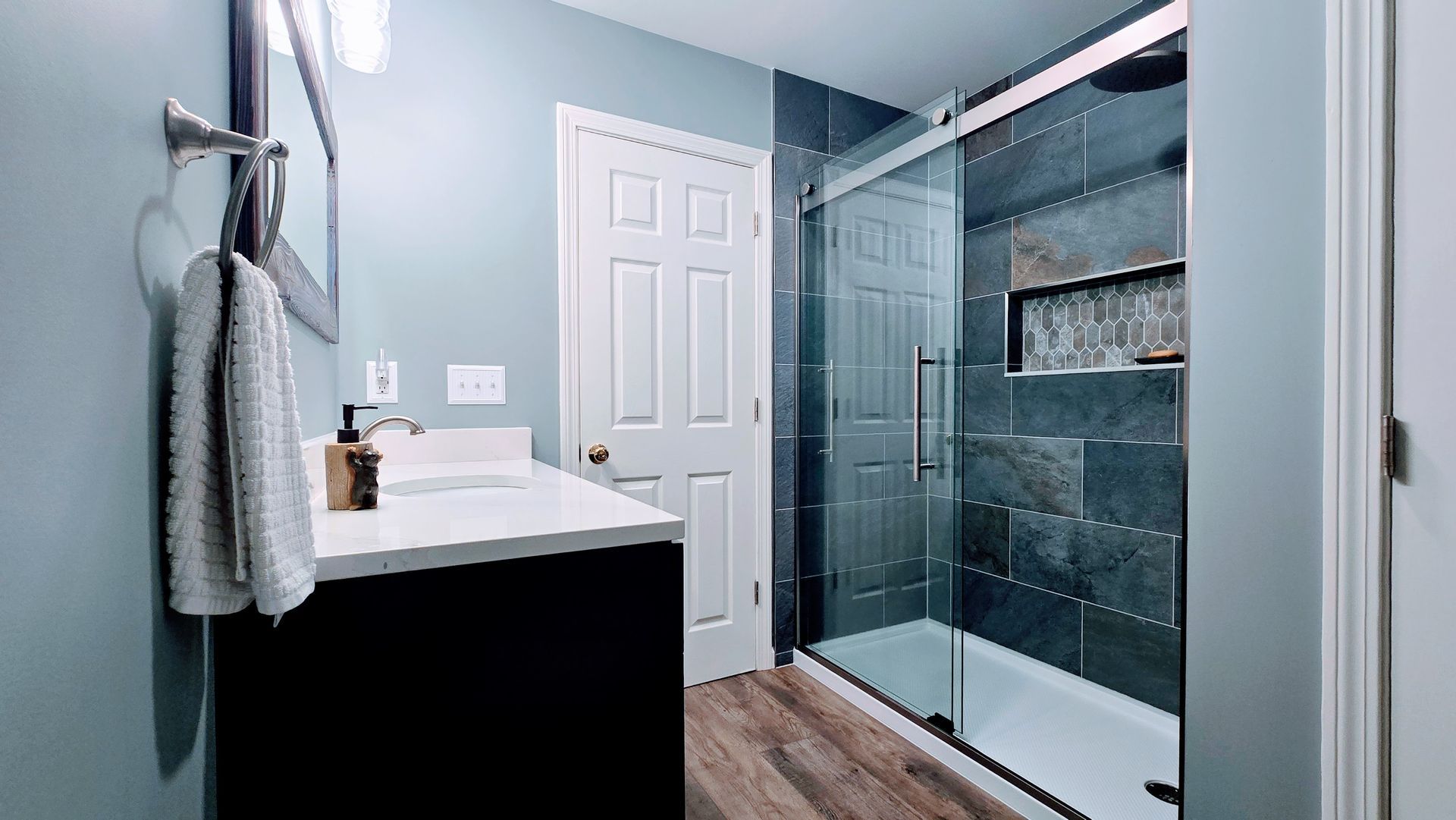 Modern bathroom with glass shower, vanity sink, and gray walls. By First Choice Bathroom Remodeling done in Plainville CT.