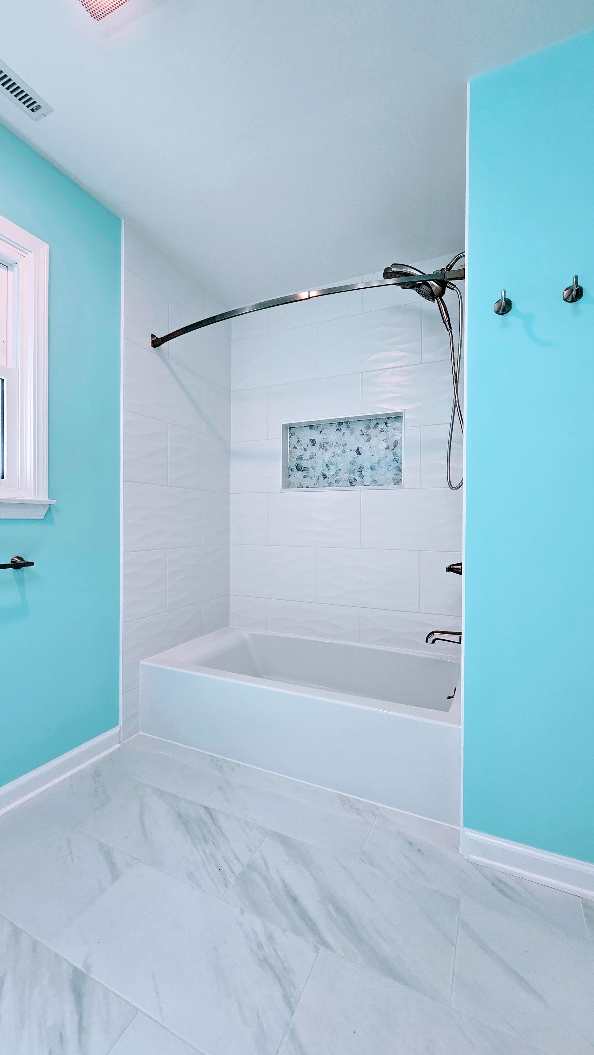 Bright bathroom with white tub, teal walls, and marble-look floor. By First Choice Bathroom Remodeling done in Southbury, CT.