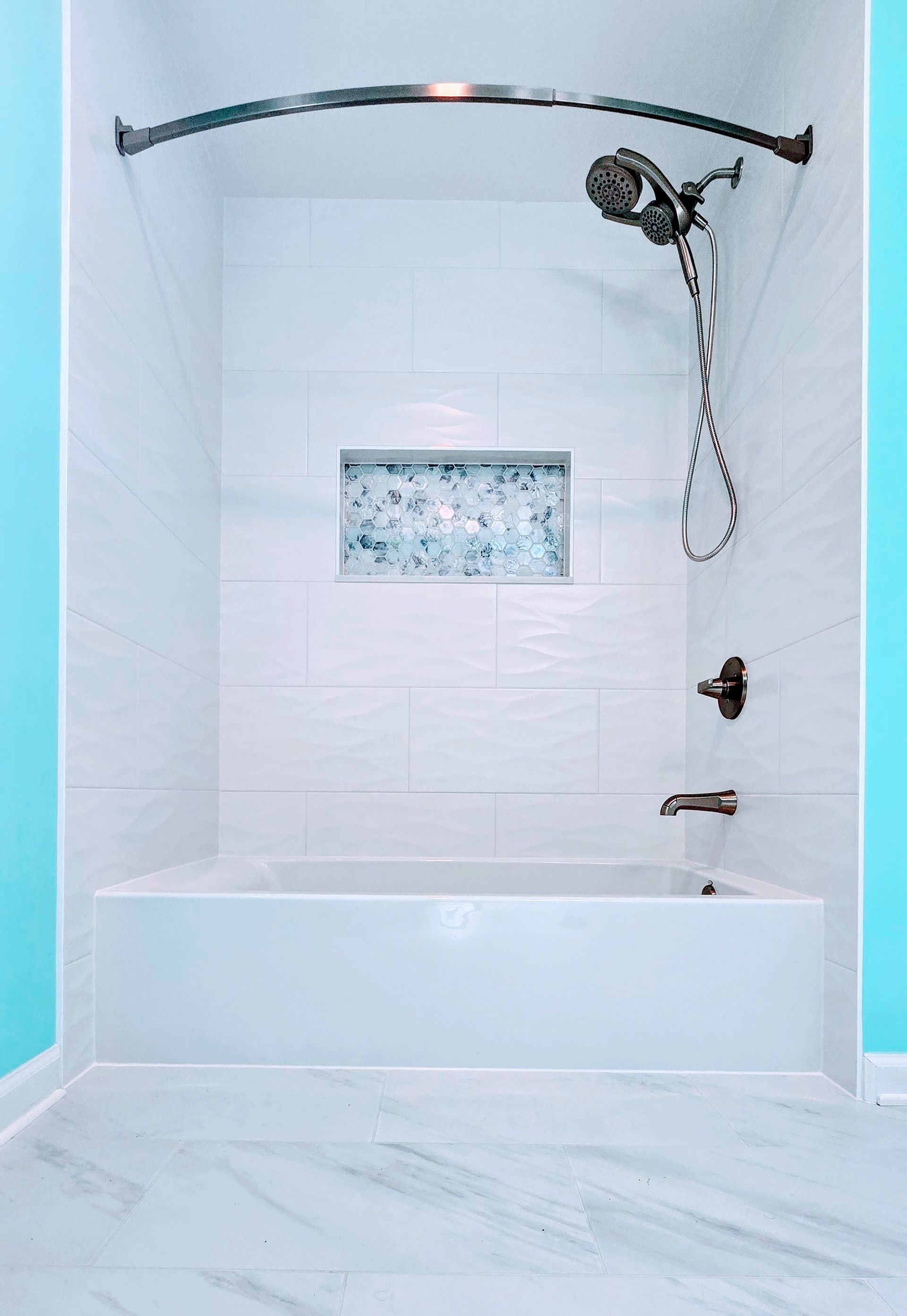White tiled shower stall with bathtub, handheld showerhead, and small mosaic window. Southbury CT