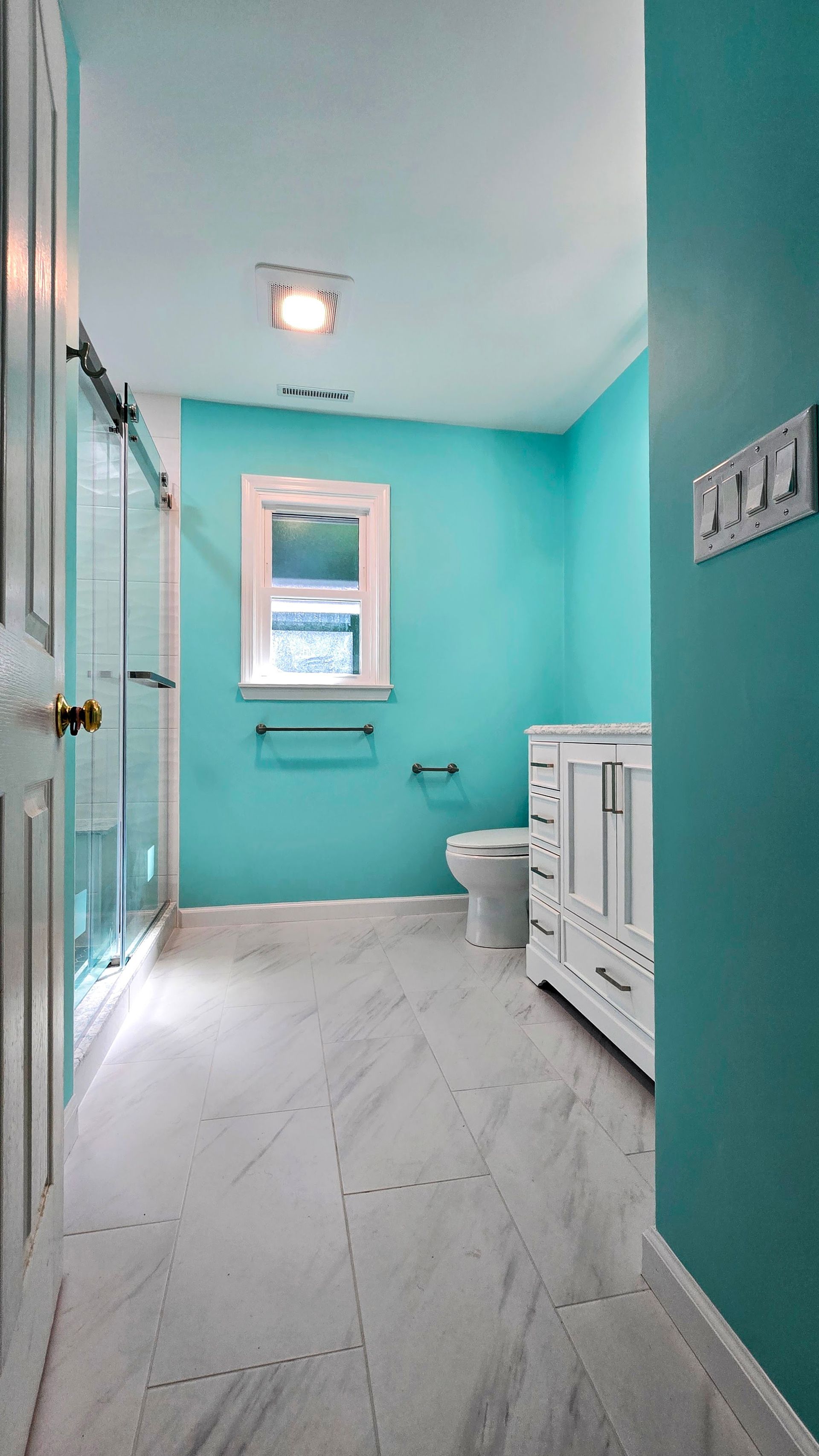 Teal bathroom with white vanity, toilet, window, and gray tile floor. Southbury CT