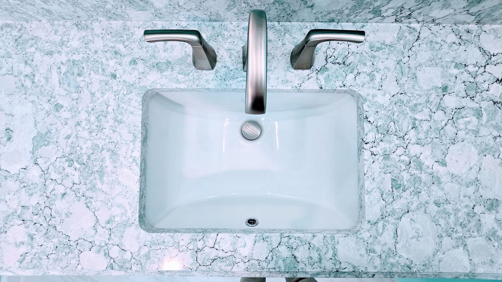 White rectangular bathroom sink with chrome faucet on a light marble countertop, top view. Southbury CT