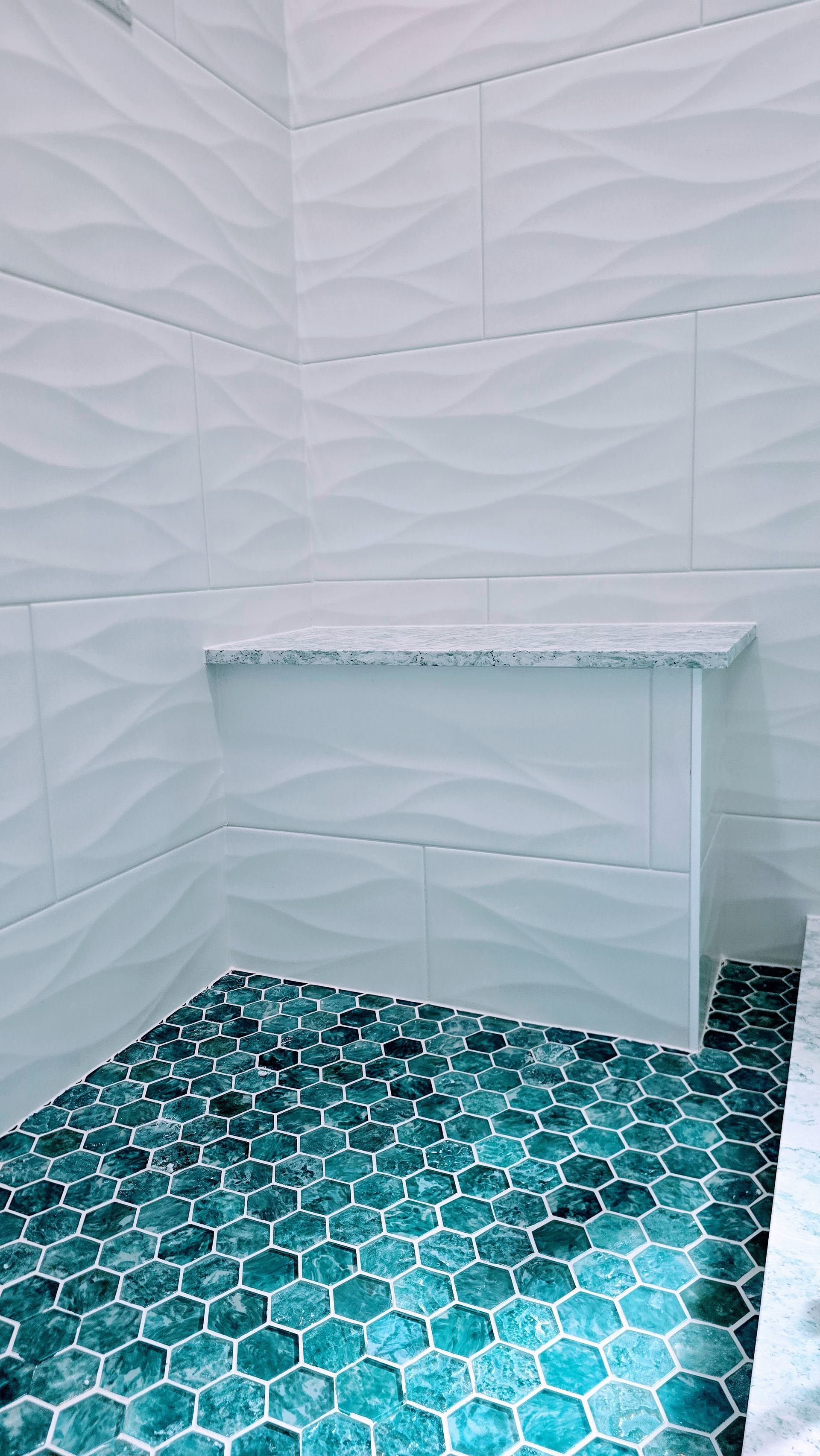 White marble vanity with floral pattern, above teal mosaic tile flooring in a bright bathroom. Southbury CT