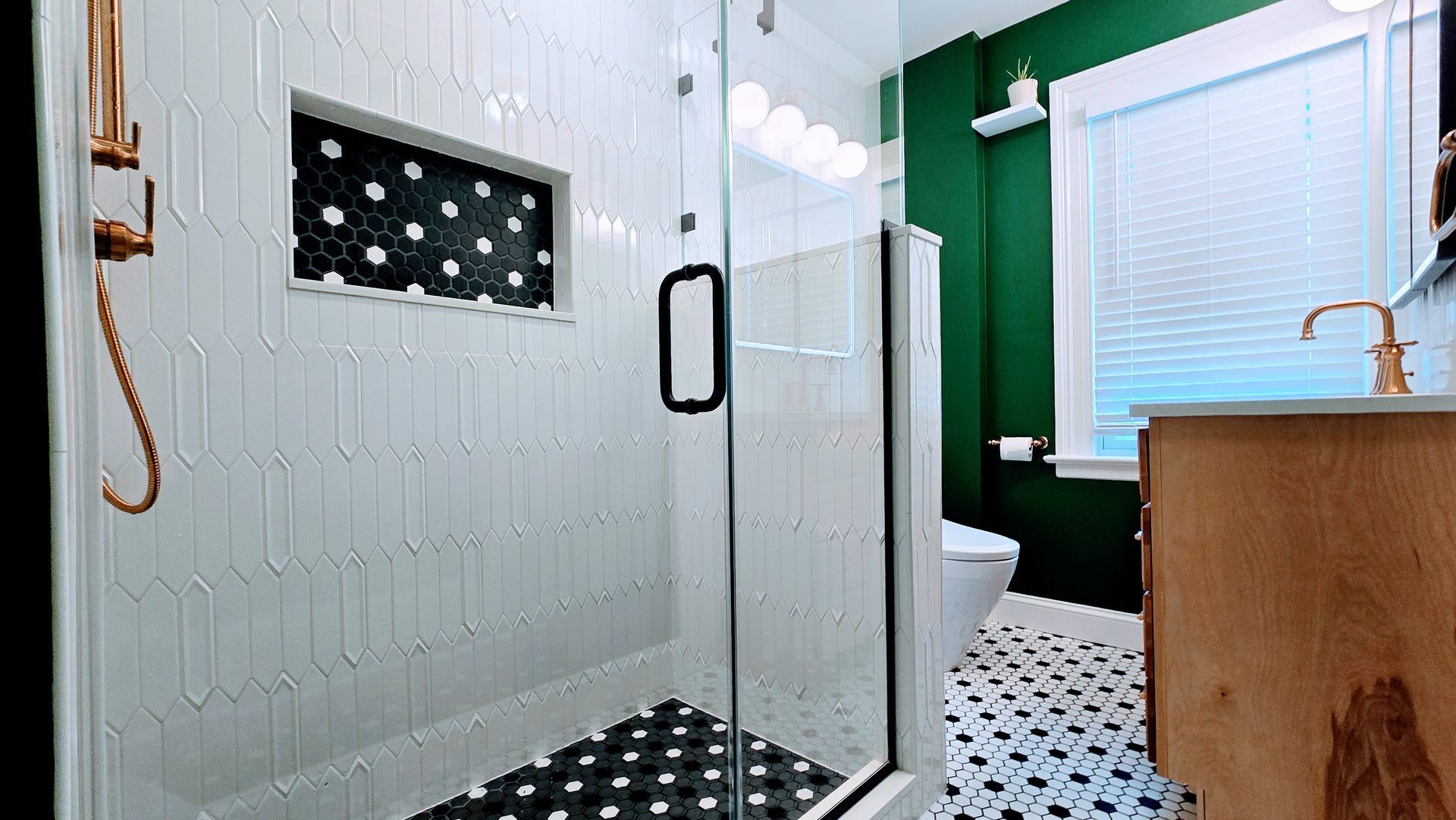Modern bathroom with glass shower, white tile, black floor accents, and a wooden vanity. Manchester CT