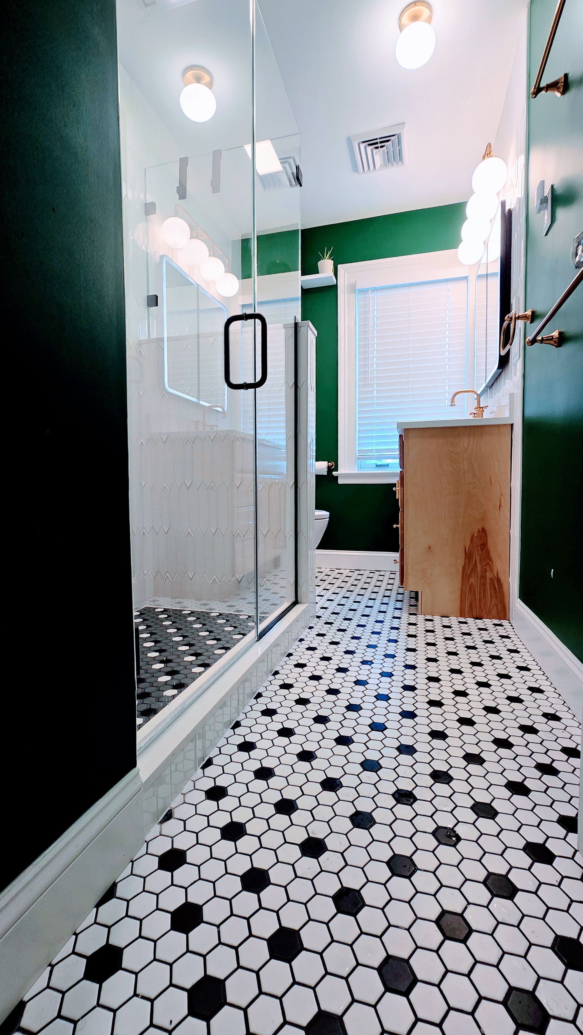 Narrow bathroom with white hex tile floor, glass shower on left, and window at the back. Done by First Choice Bathroom Remodeling done in Manchester, CT.