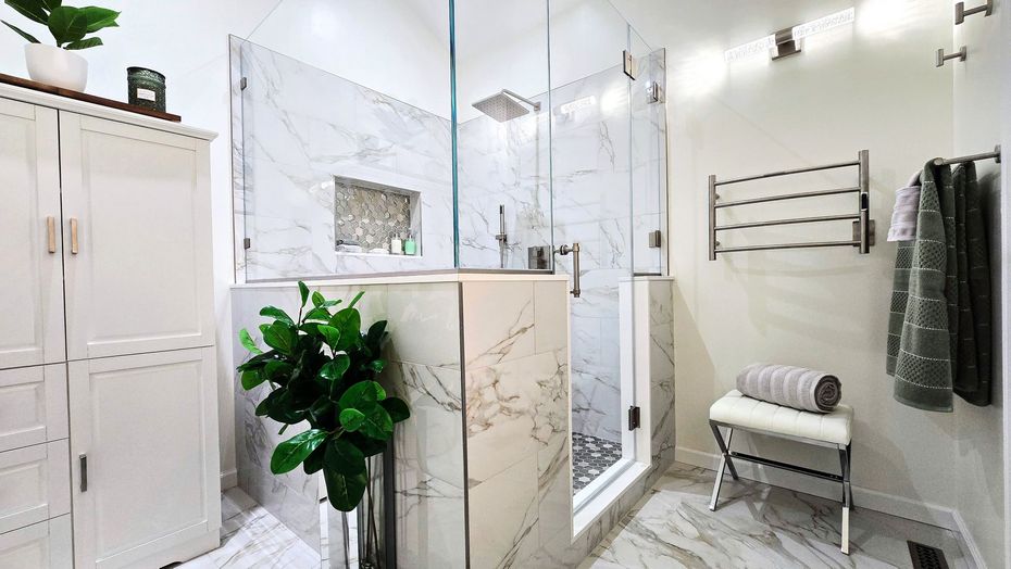 Bright white bathroom remodel in Prospect, CT with glass shower, marble vanity, towel rack, and potted plant