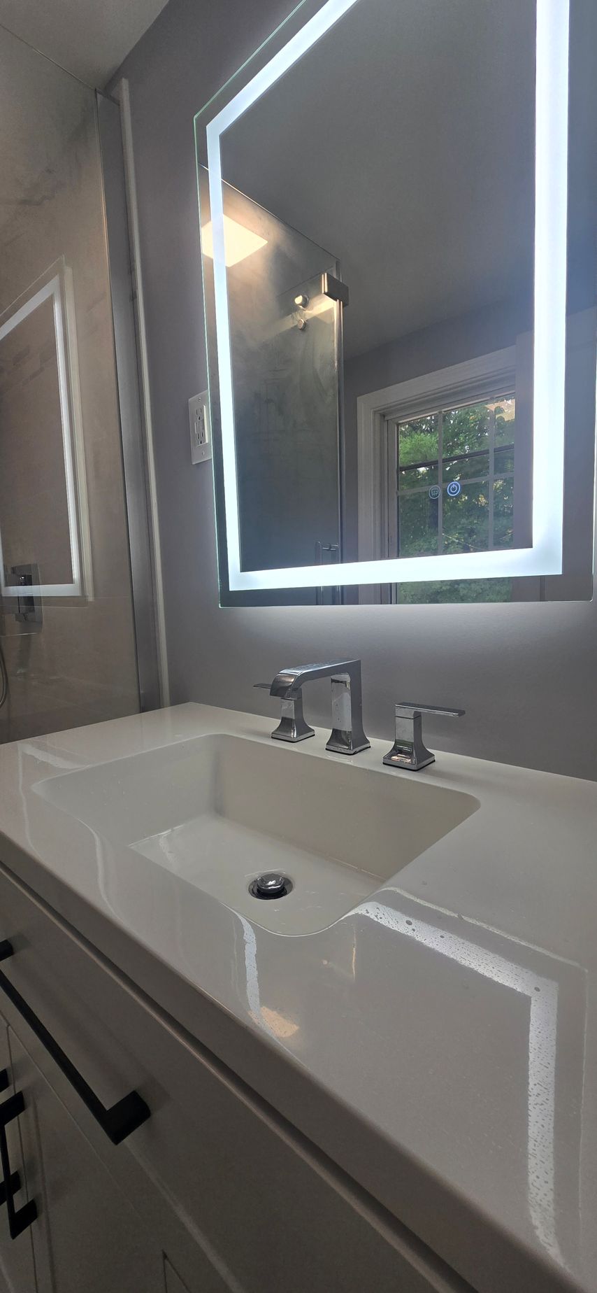 Modern bathroom vanity with illuminated mirror, white sink, and chrome faucet under soft lighting. By First Choice Bathroom Remodeling done in Norfolk, CT.