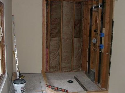 A bathroom under construction with a bucket of water and a level.