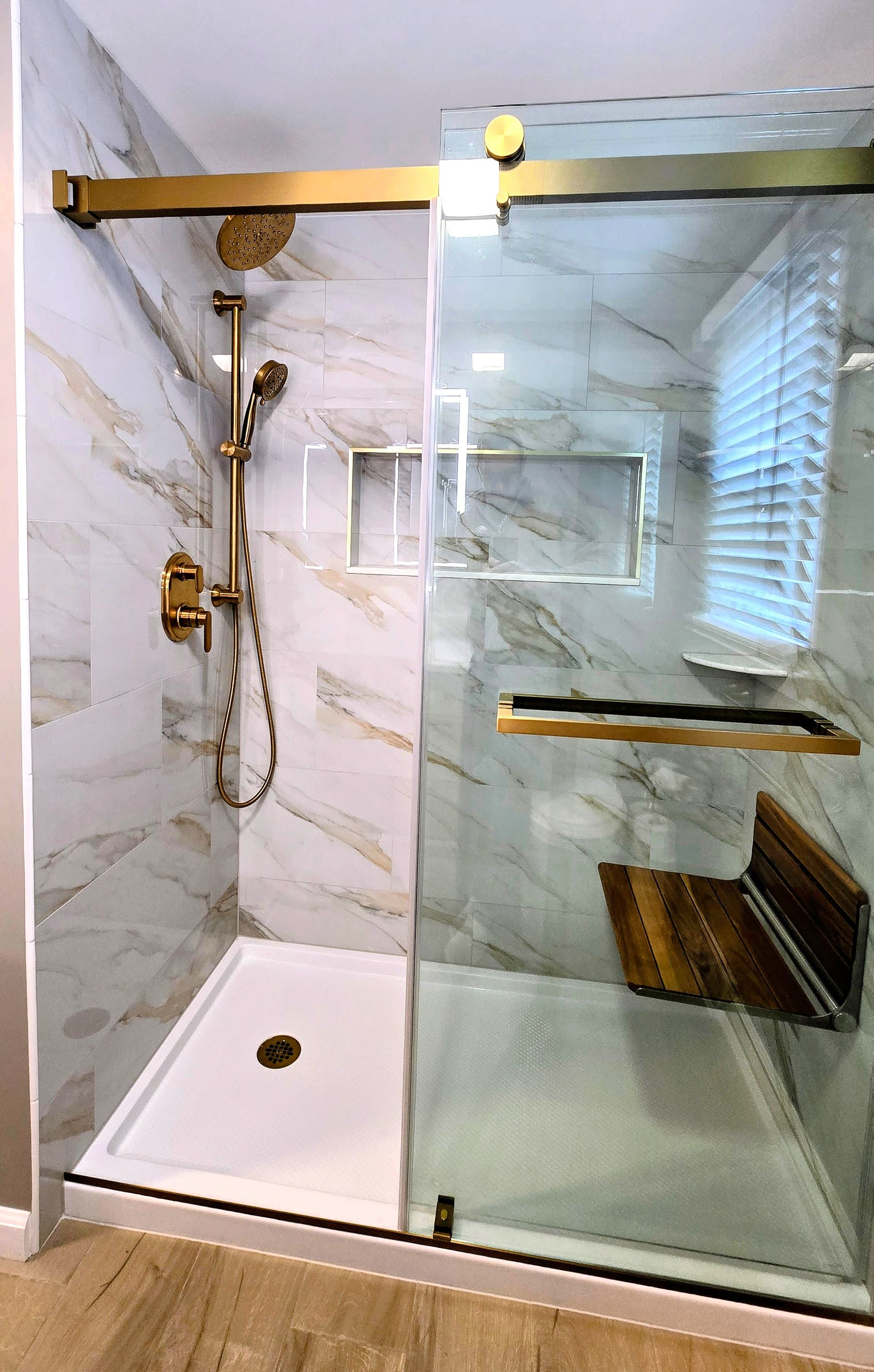 Modern bathroom remodel in Plainville, CT with dark gray tiled shower wall and built-in shelf above a white tub.