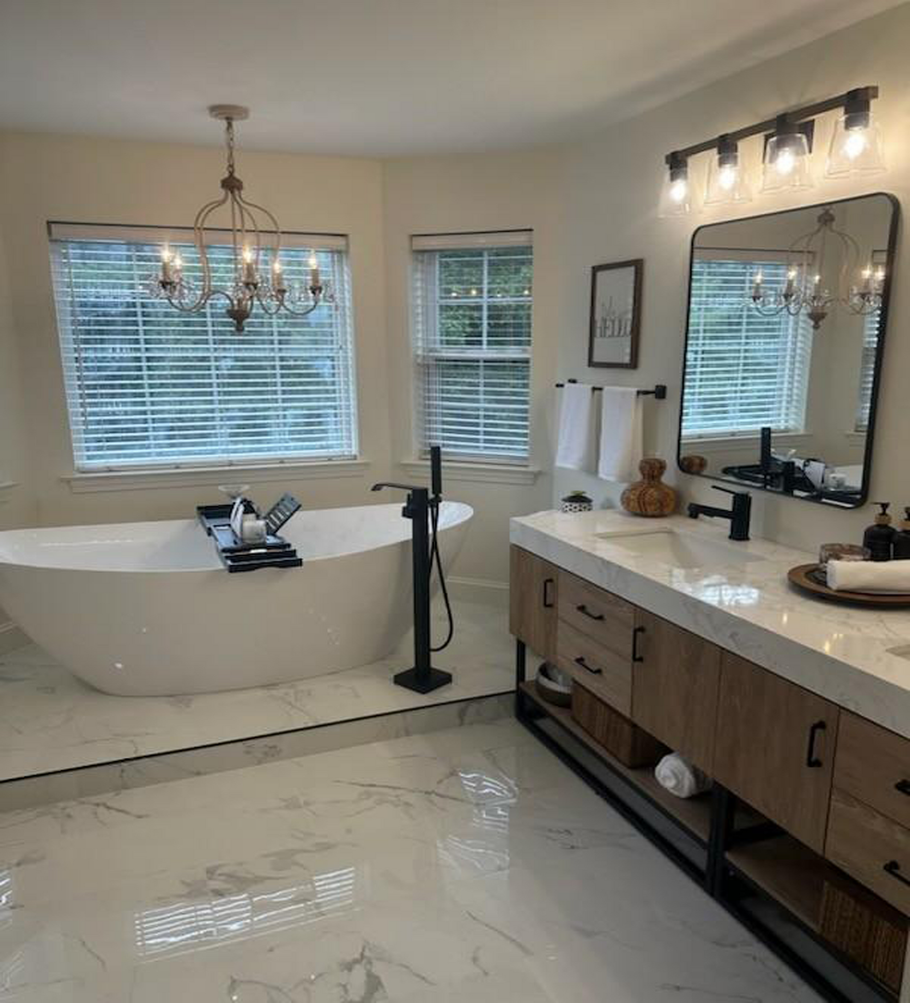 Modern bathroom in Burlington, CT with a white soaking tub, double vanity, and marble-look tile flooring.