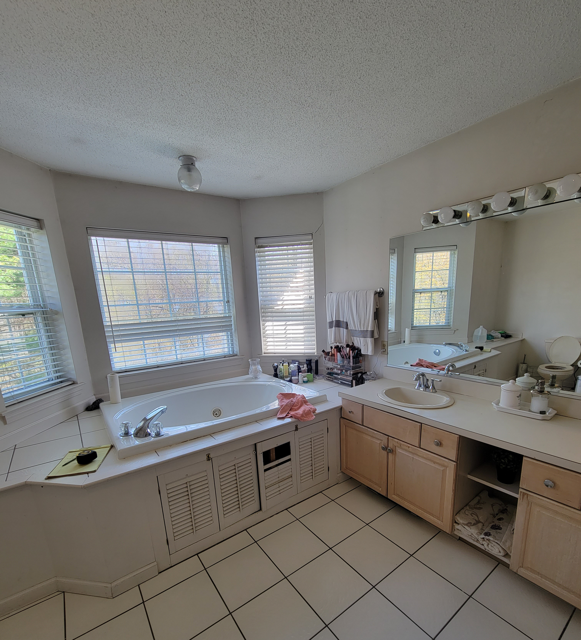 A bathroom with a tub , sink , mirror and window.