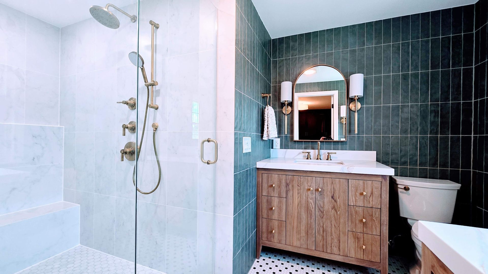 Modern bathroom in Glastonbury, CT with glass shower, dark tiled walls, wood vanity, mirror, and toilet
