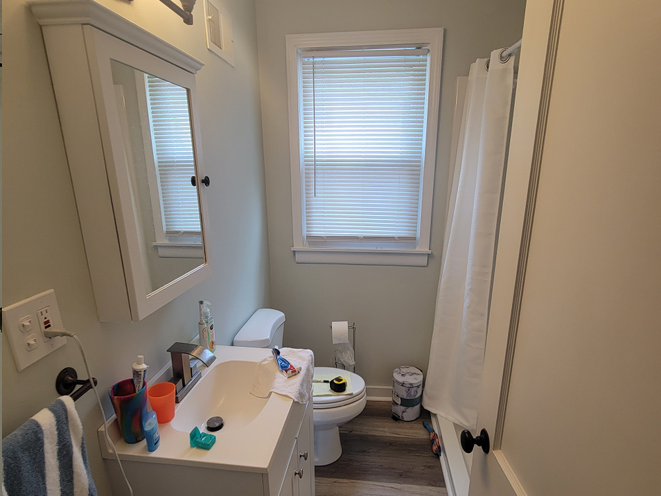 A bathroom with a toilet , sink , mirror and shower curtain.