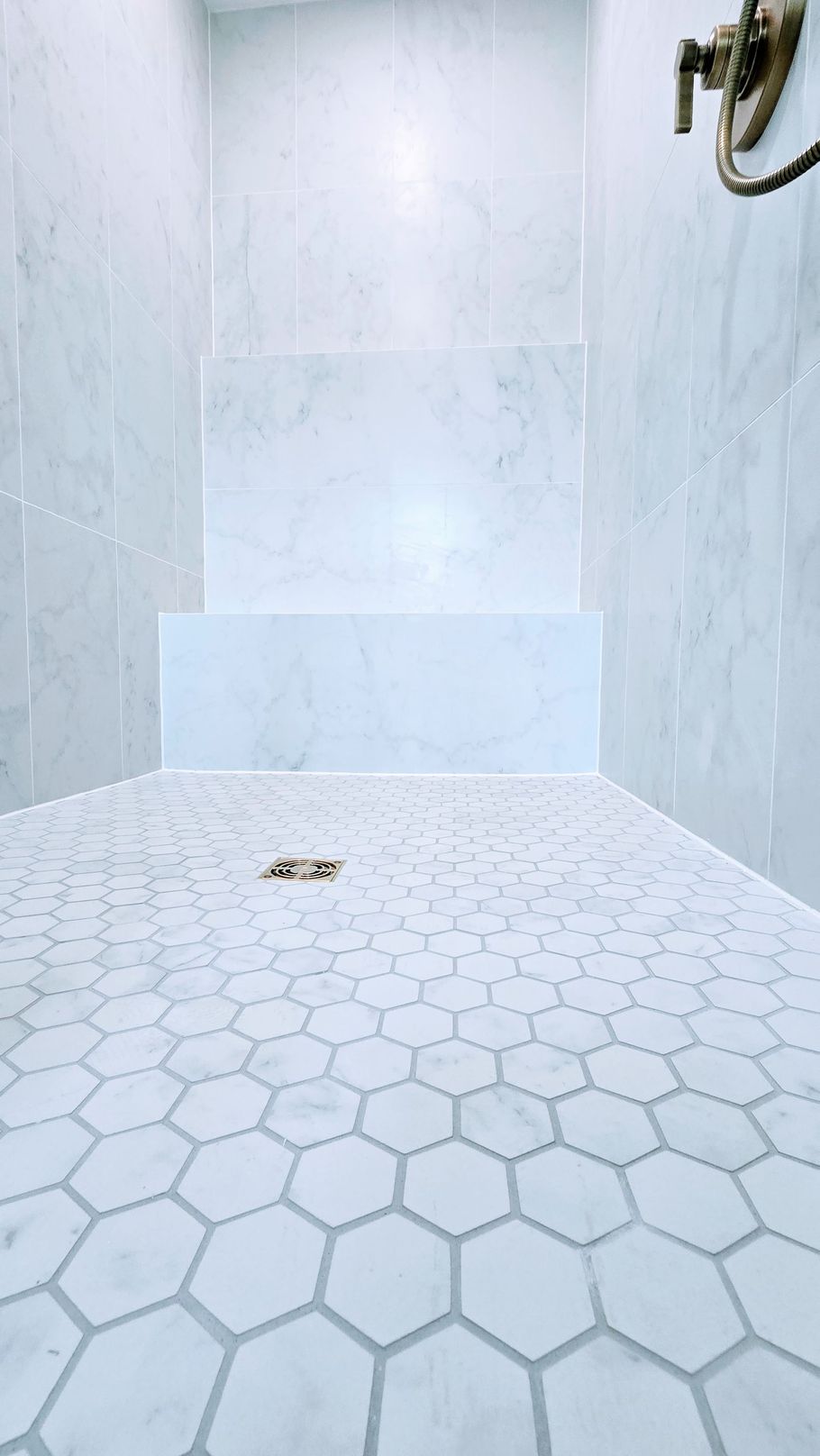 White-tiled custom walk-in shower in Glastonbury, CT bathroom remodel with hexagonal floor tiles and a small drain.