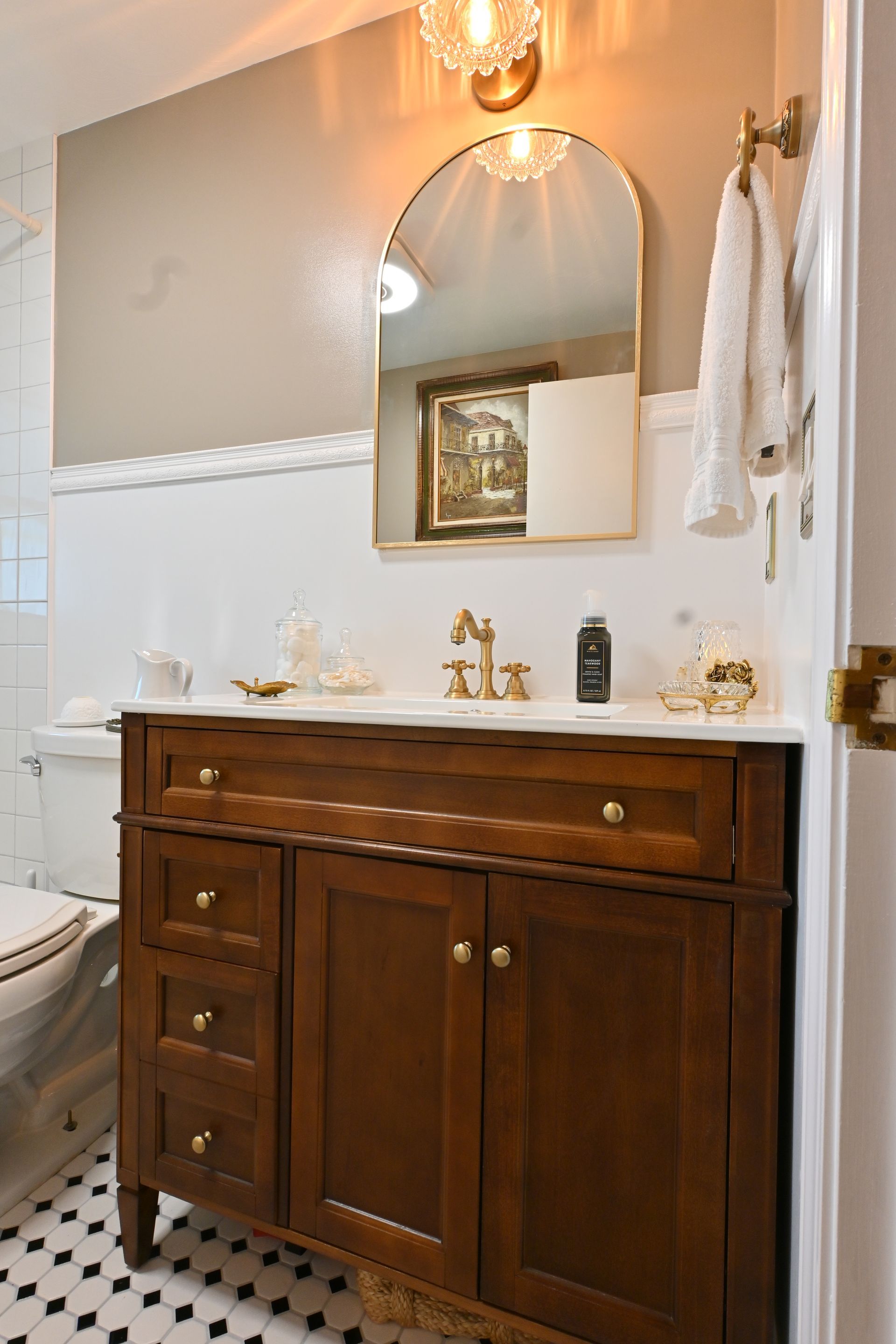 Dark wood bathroom vanity with marble top, round mirror, and white walls in a bright bathroom