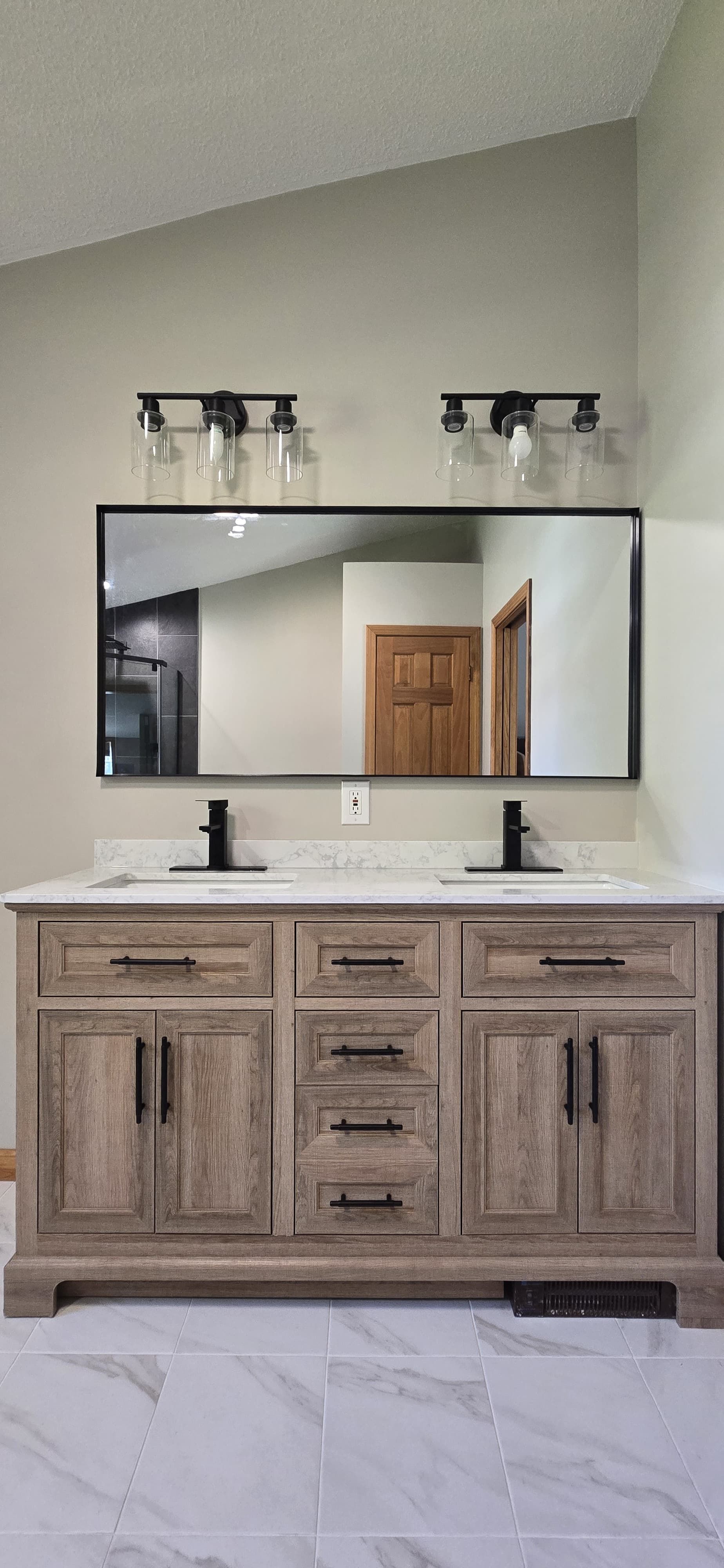 Modern double vanity bathroom with wood cabinets, large mirror, and wall sconces. By First Choice Bathroom Remodeling done in Cheshire, CT.