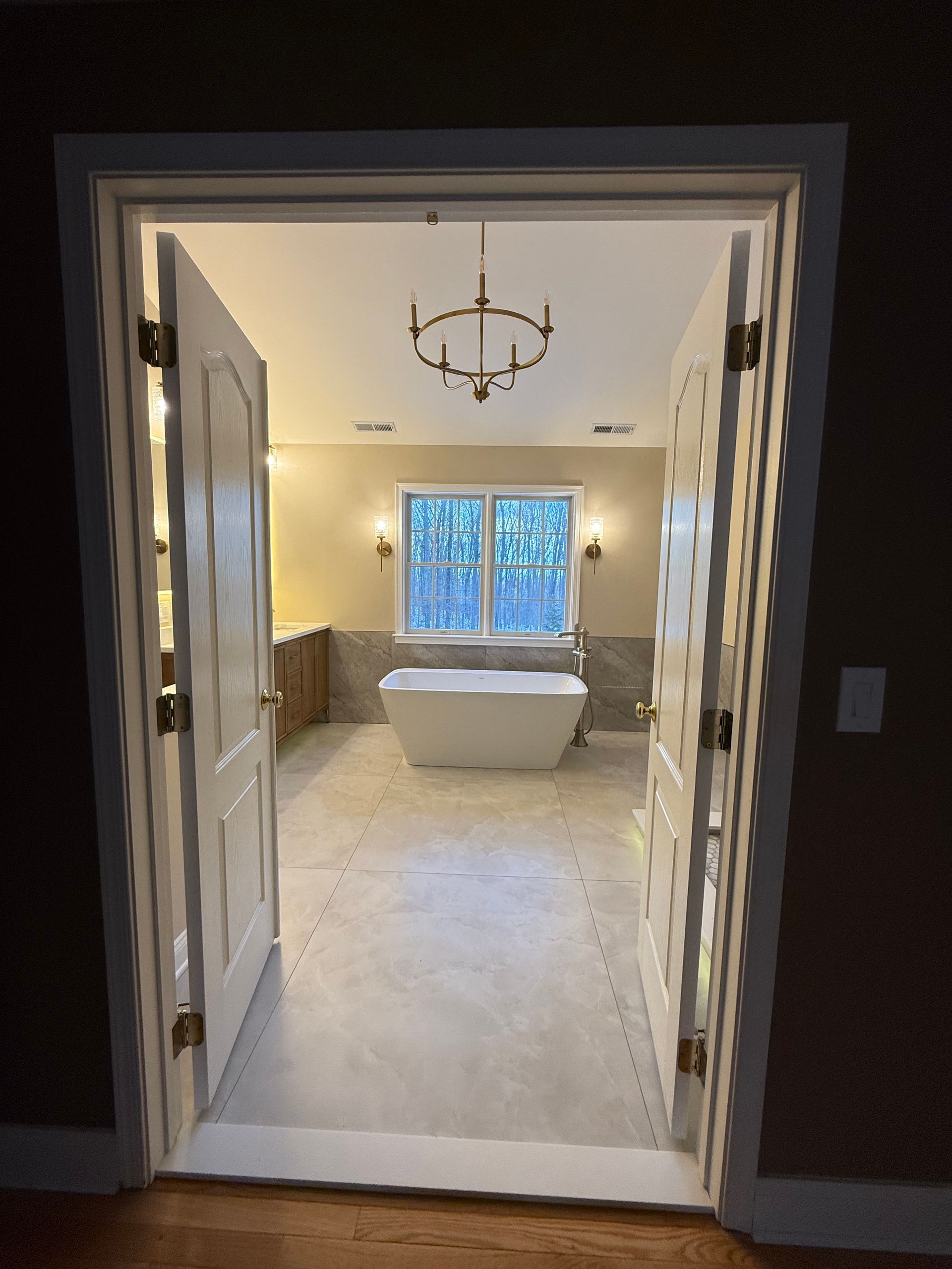 A bathroom with a tub and a chandelier hanging from the ceiling.