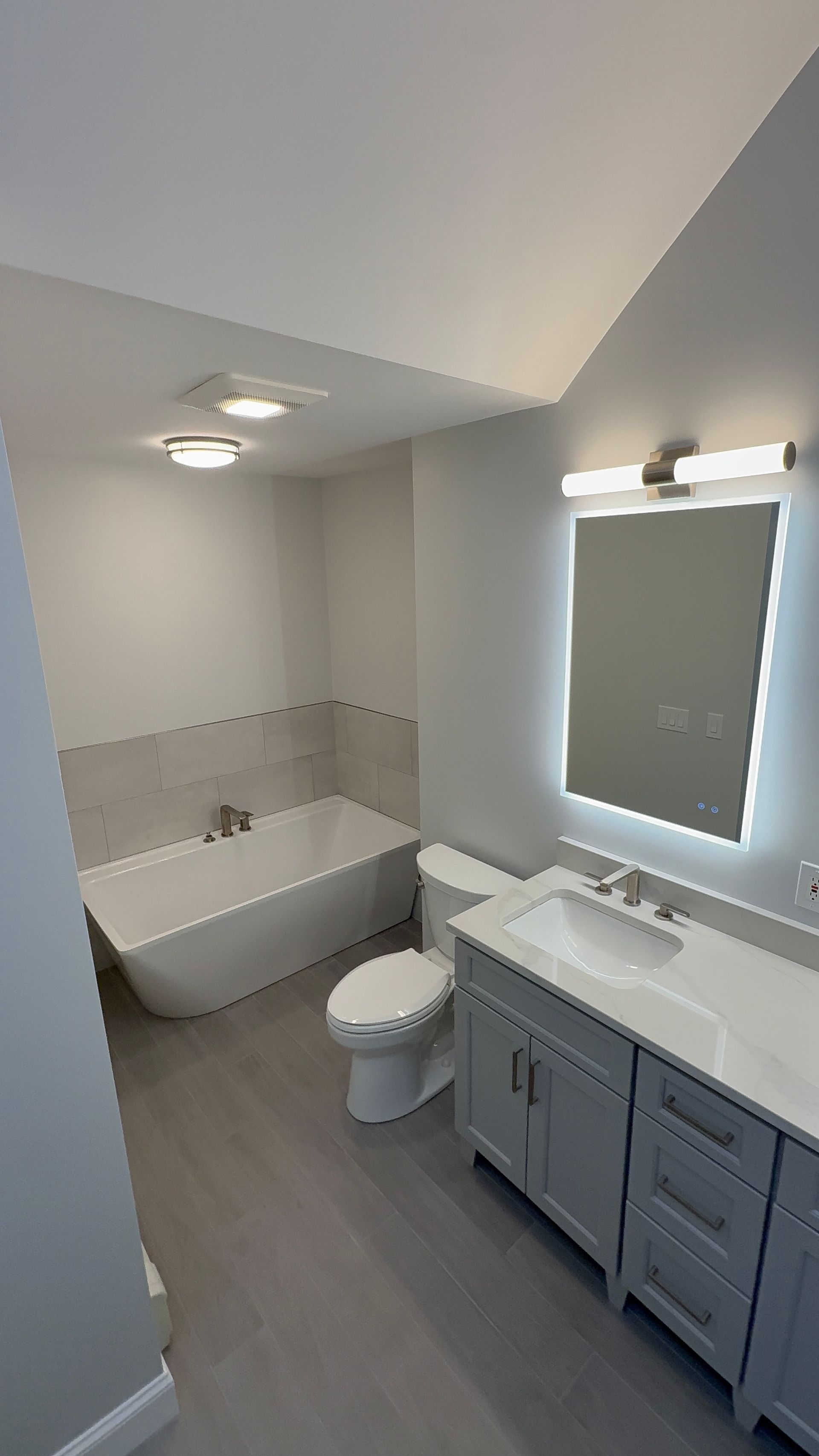 A bathroom with a tub , toilet , sink and mirror.