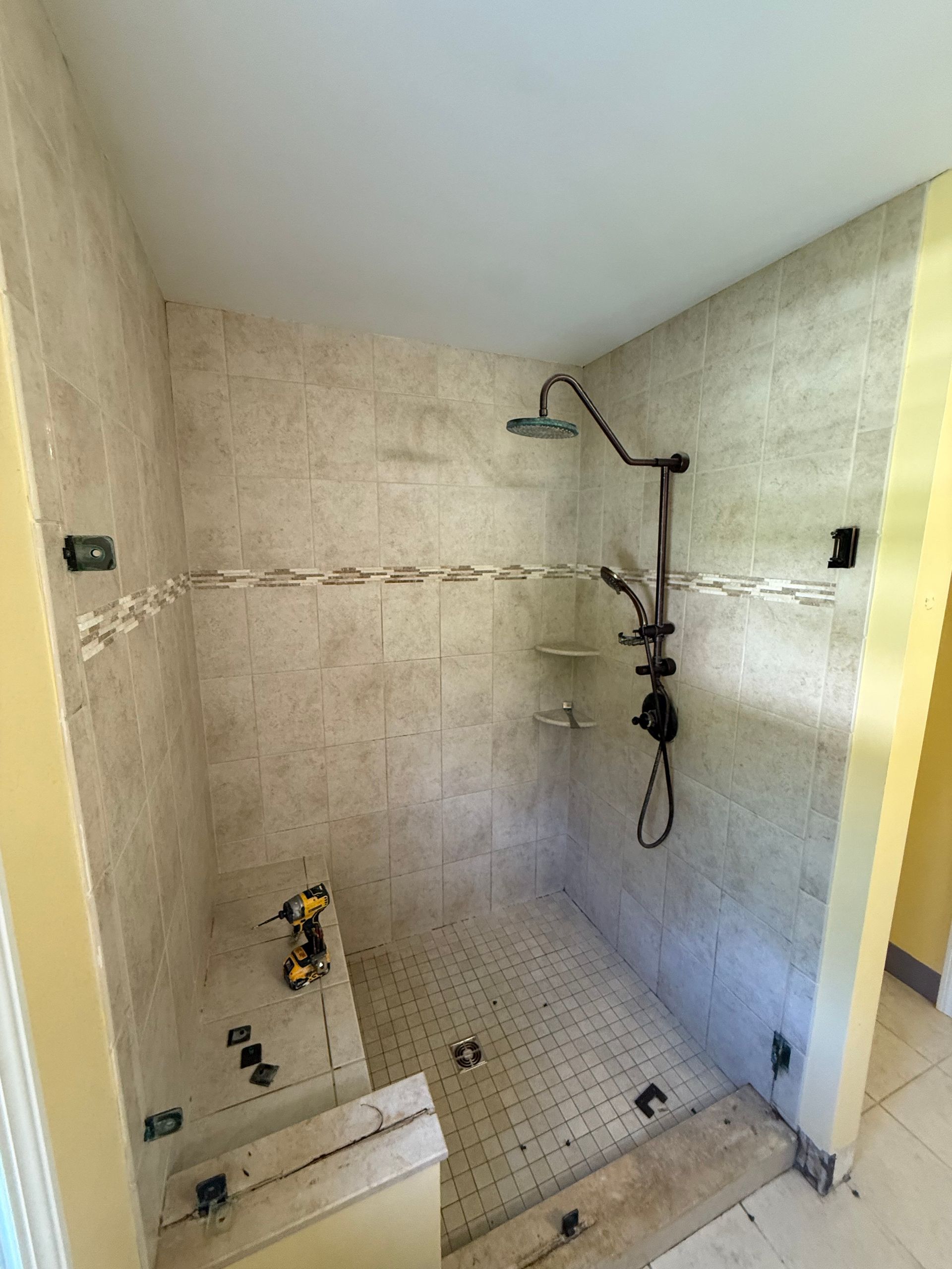 A shower with a built in shelf and a shower head