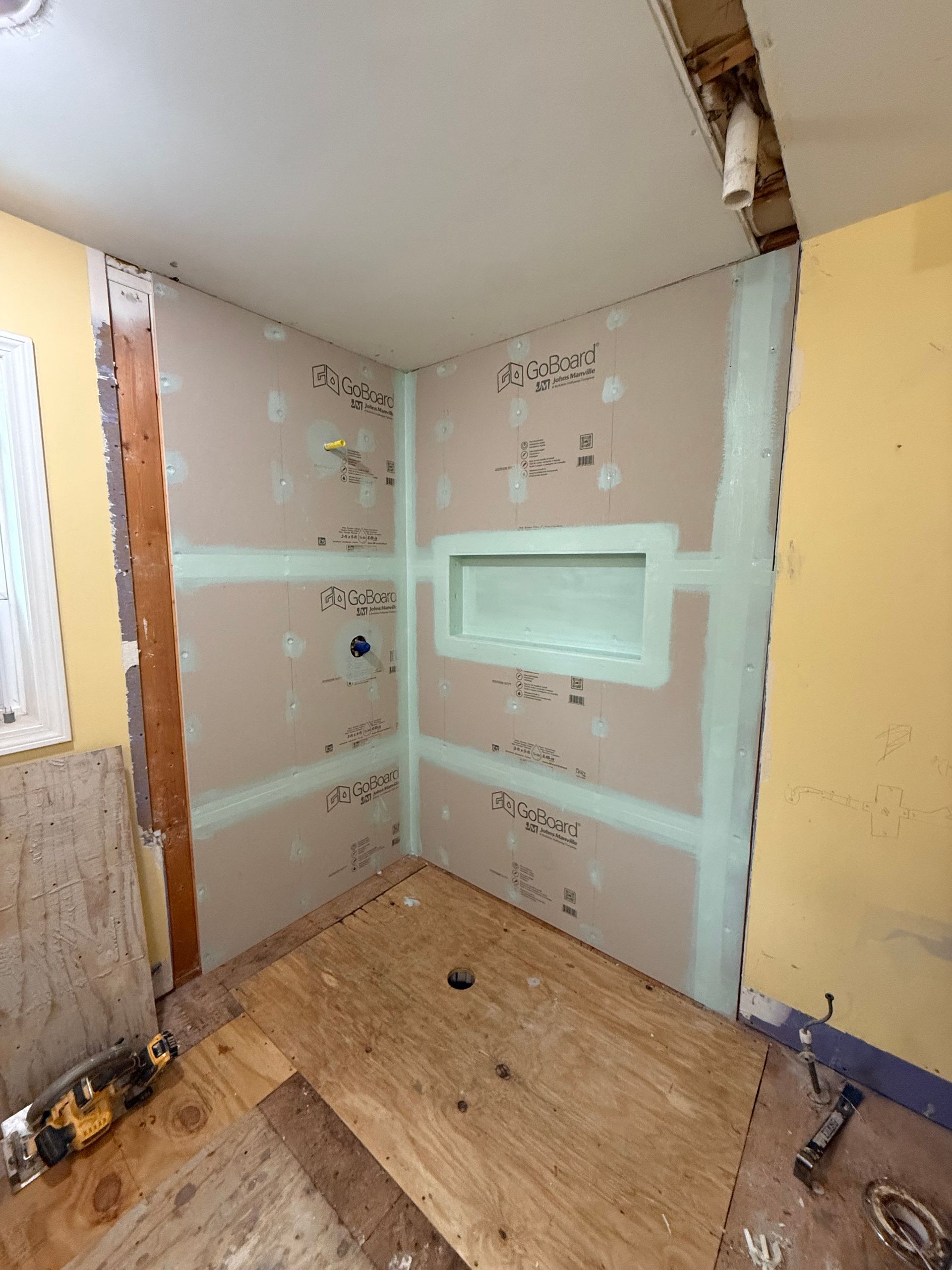 A bathroom is being remodeled with a shower stall and a niche in the wall.