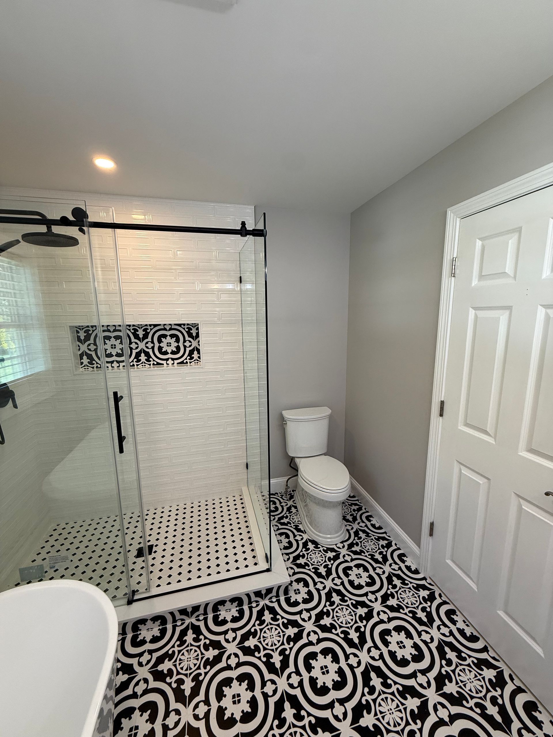 A bathroom with a shower , toilet , sink and mirror.
