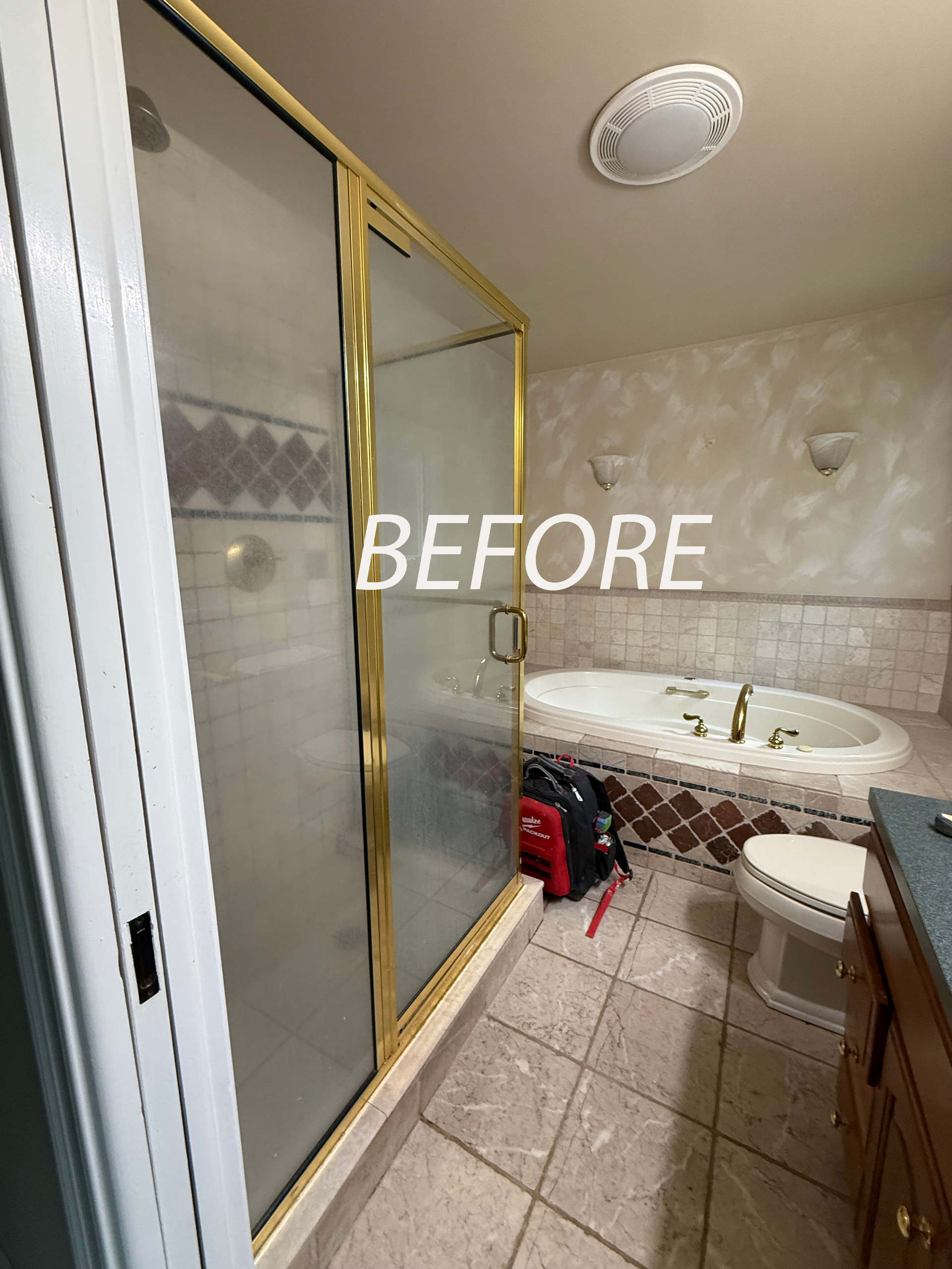 Bathroom in Avon, CT with sliding glass shower doors, large tub, sink, and tiled floor, labeled “BEFORE”