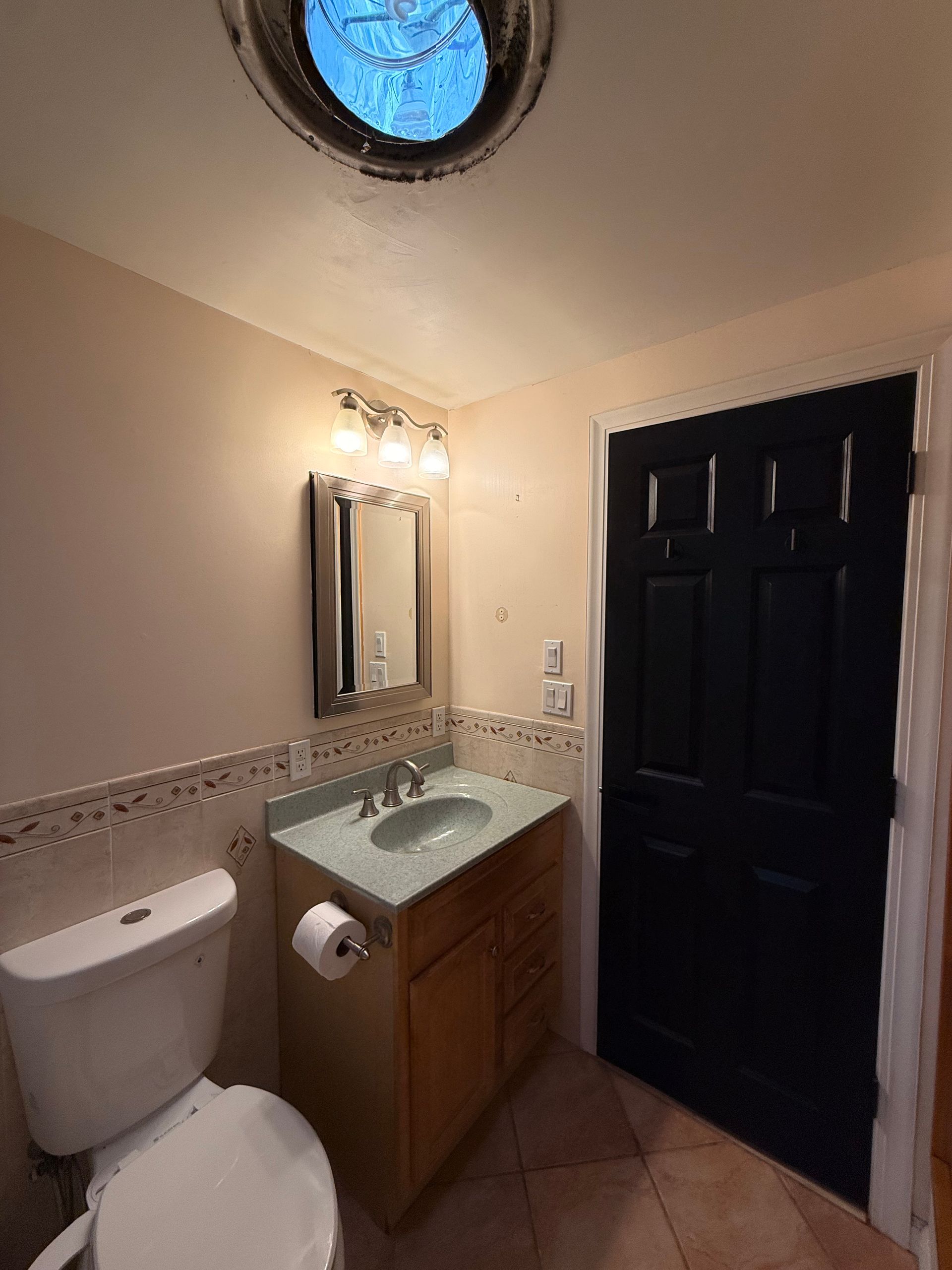 Small West Hartford bathroom with a sink, toilet, and cabinet. Gray walls and dark floor.