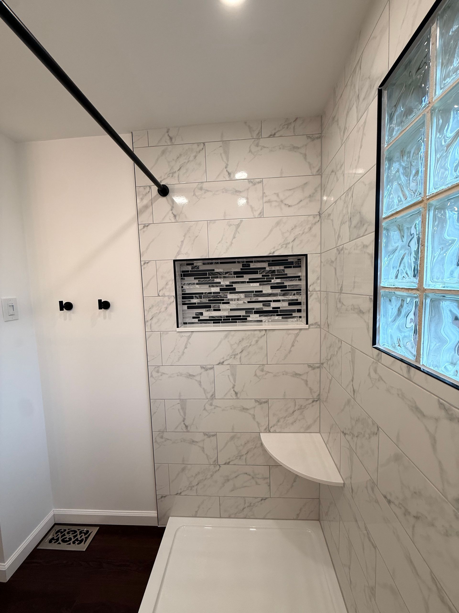 Berlin bathroom with a built-in tub, shower fixtures, and a small glass block window.